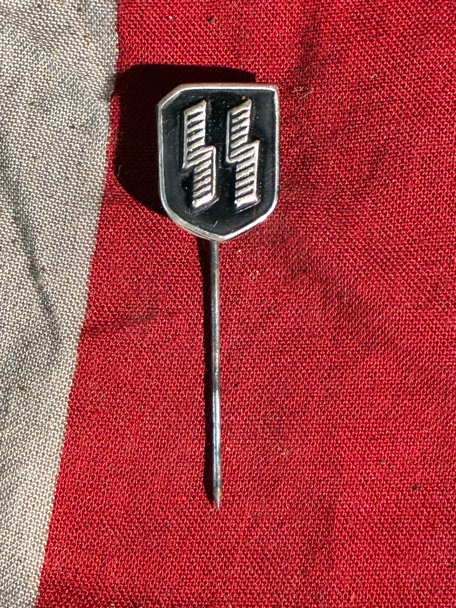 WW2 German SS Membership Stickpin (Schutzstaffel Insignia), ca. 1930s–1940s: This small enamel stickpin bears the insignia of the Schutzstaffel (SS), the paramilitary organization that played a central role in enforcing the racial policies and mass atrocities of Nazi Germany. 