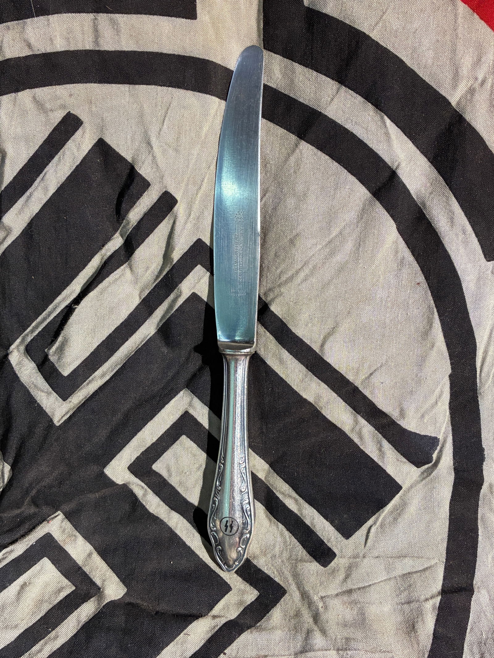 WW2 German SS-Marked Table Knife from Waffen-SS Facilities (c. 1930s–1940s): This table knife, manufactured by J.A. Henckels, Solingen, bears the engraved SS double-rune emblem on the handle—an insignia used by the paramilitary wing of the Nazi regime. Such utensils were com