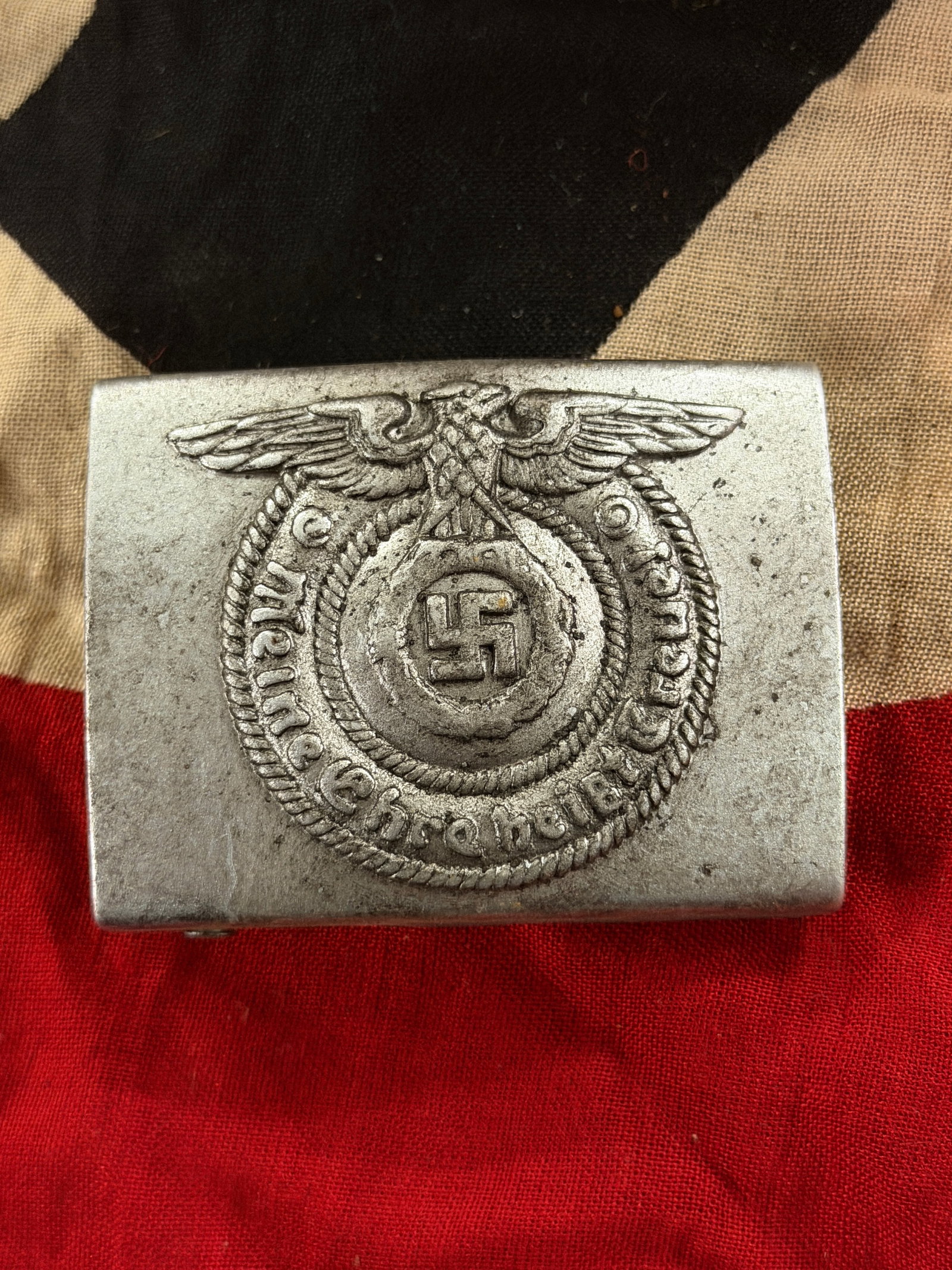 WW2 German Waffen-SS Enlisted Man’s Belt Buckle: This metal belt buckle was worn by enlisted personnel of the Waffen-SS, the military arm of the SS during the Second World War. Cast in a light alloy, it features an eagle clutching a wreath enclosing
