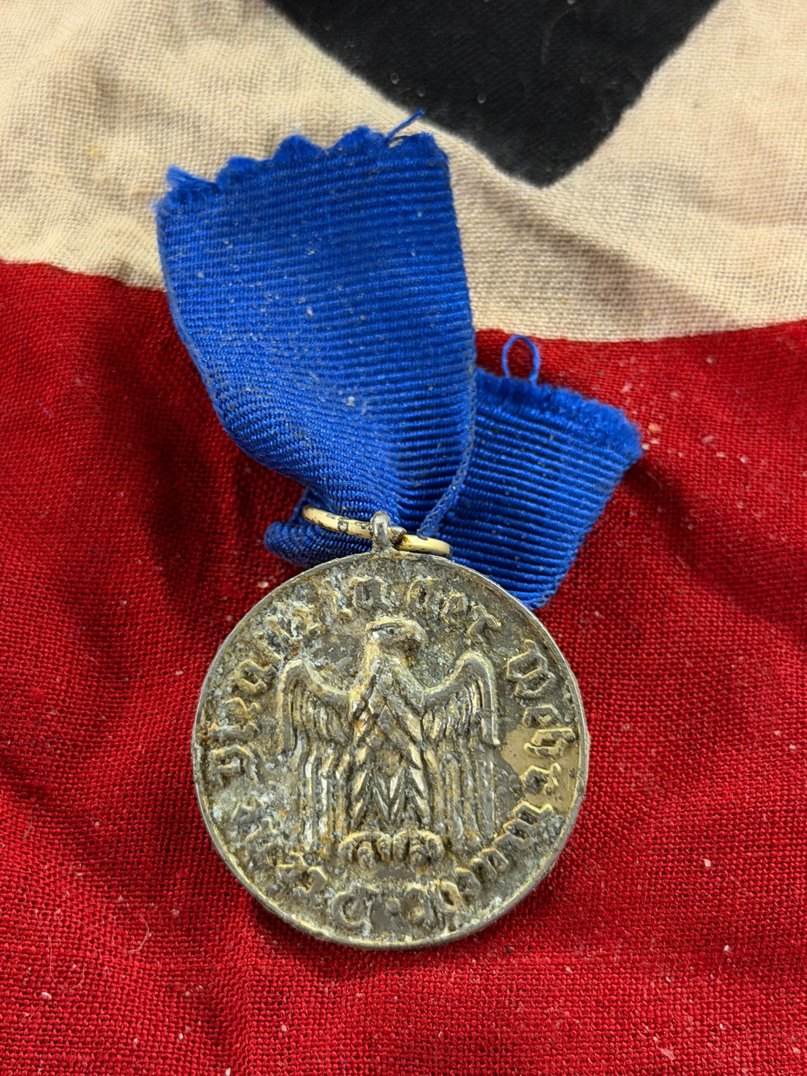 WW2 German 12-Year Long Service Medal: This medal is a German long-service decoration awarded for twelve years of faithful service in the armed forces during the World War II era. Suspended from a blue ribbon, the medal bears the German ea