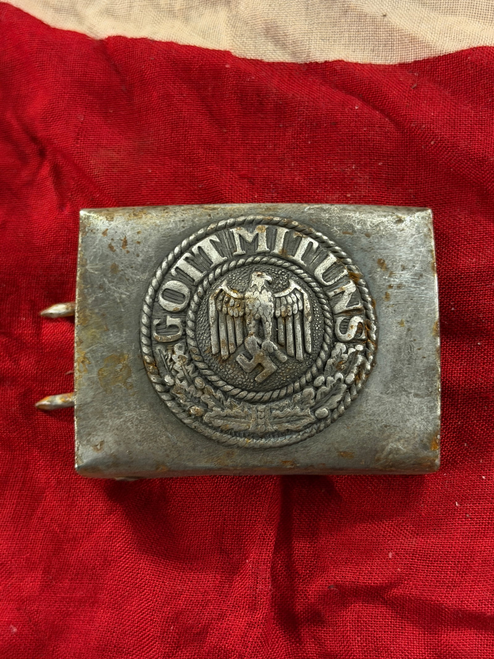 WW2 German Belt Buckle of the National Socialist German Workers’ Party (NSDAP): This rectangular metal belt buckle bears the circular emblem of the National Socialist German Workers’ Party (NSDAP), featuring a stylized eagle grasping a wreath enclosing a swastika, surrounded by