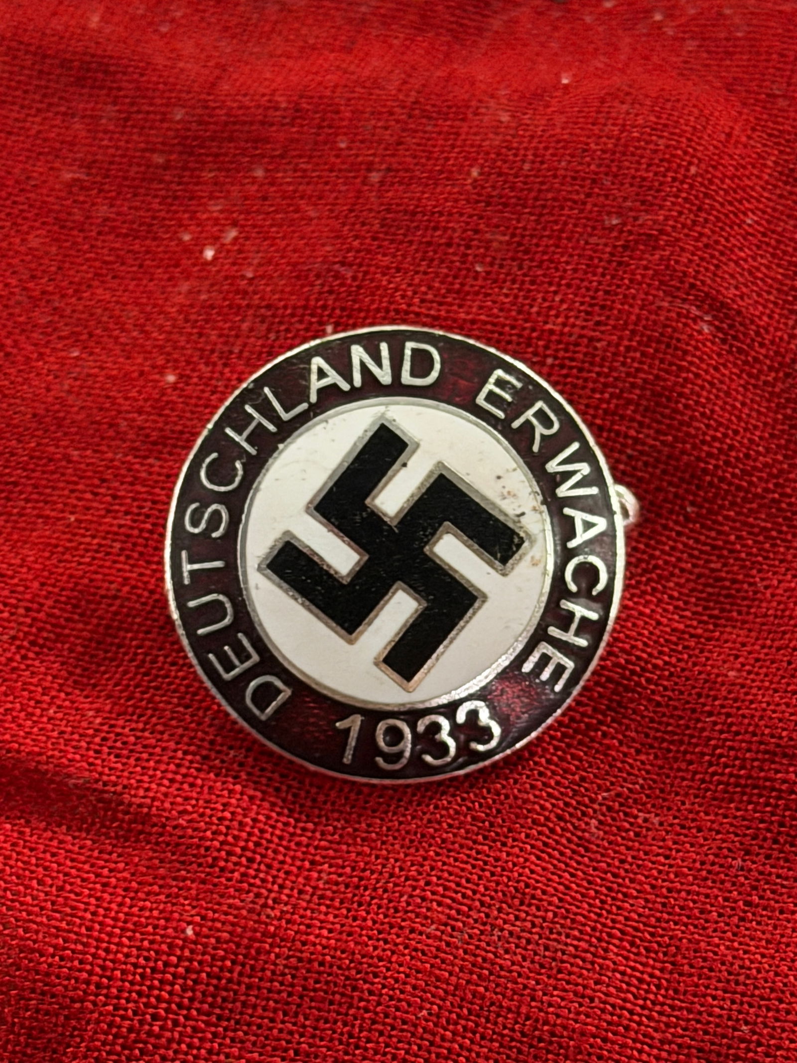 WW2 German National Socialist Party Membership Badge (Deutsche Arbeitsfront / NSDAP), 1933: his circular enamel badge bears the inscription “DEUTSCHLAND ERWACHE 1933” (“Germany Awake 1933”), a slogan associated with the early rise of the National Socialist movement following