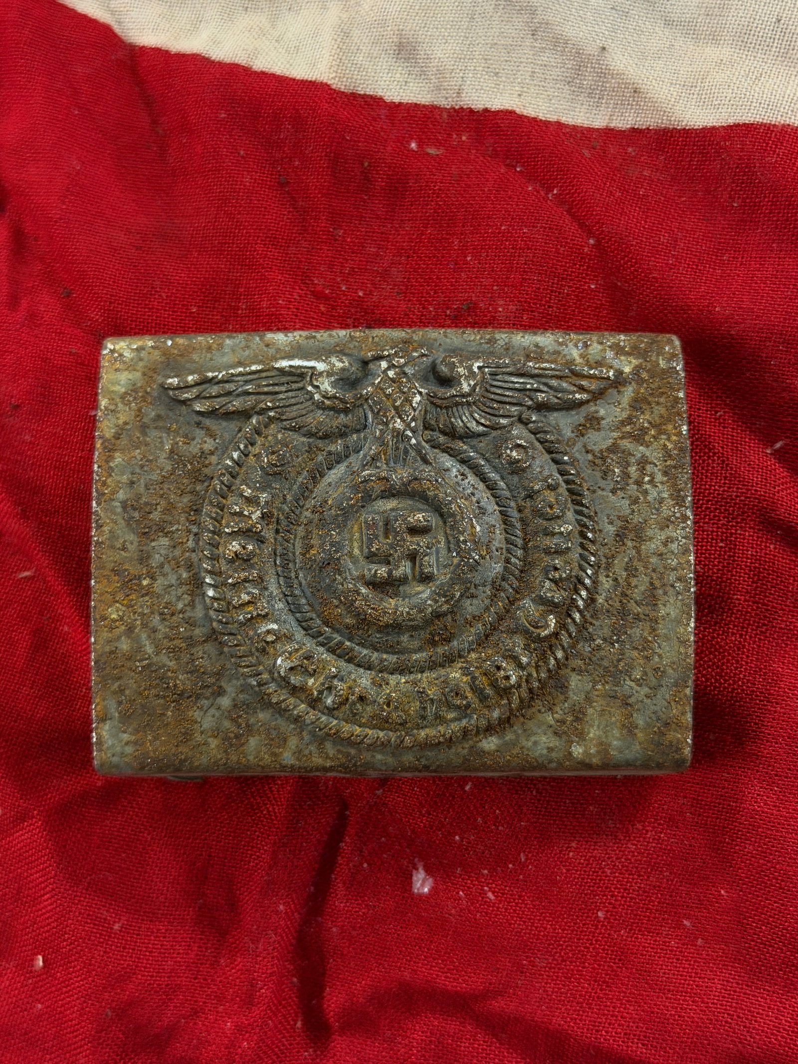 WW2 German Waffen-SS Enlisted Man’s Belt Buckle (Koppelschloss): This rectangular metal belt buckle is an uniform accoutrement of the Waffen-SS, the armed branch of the Schutzstaffel (SS) in Nazi Germany during the Second World War. The central design features a sp
