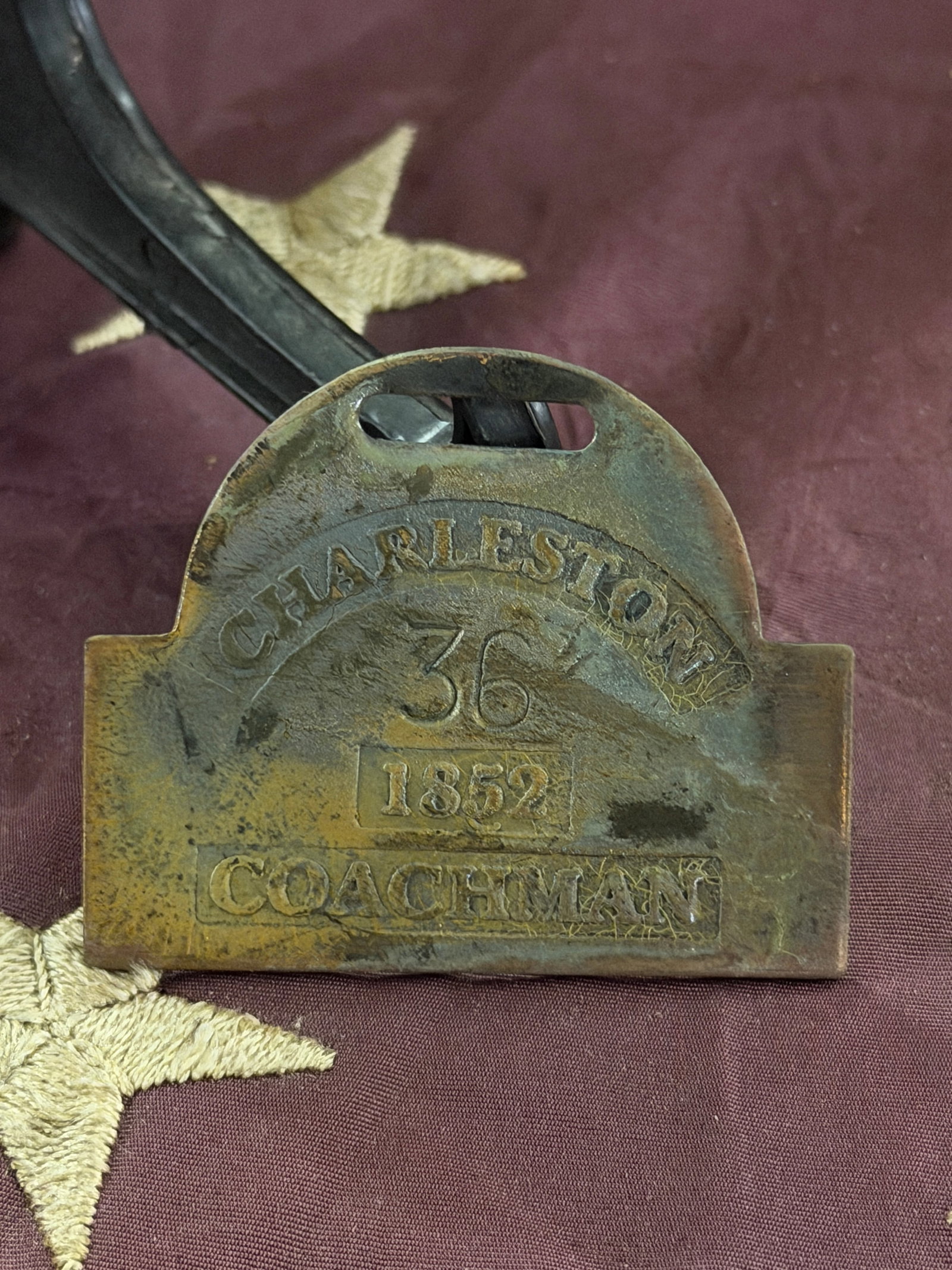 Plantation Identification Tag (“Coachman??), Charlotte, 1852: This brass plantation identification tag was issued in Charlotte, North Carolina, in 1852 and is marked “COACHMAN” with the number 36. Such tags were worn by enslaved African Americans in urba