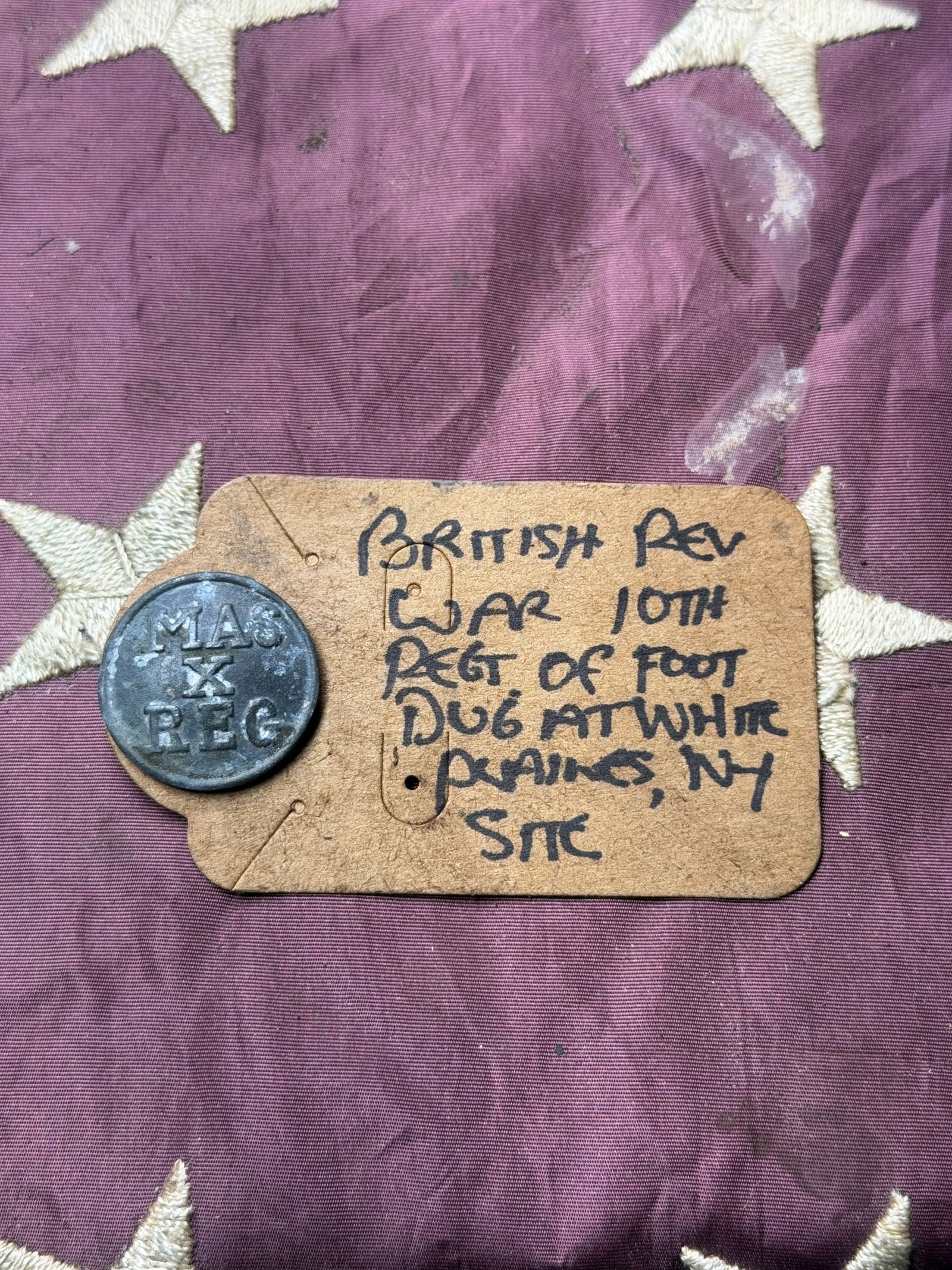 British Army Button, 10th Regiment of Foot (Lincolnshire), Revolutionary War Era: This pewter regimental button bears the raised inscription “MAS X REG”, identifying it as a British Army issue for the 10th Regiment of Foot (Lincolnshire Regiment) during the late 18th centur