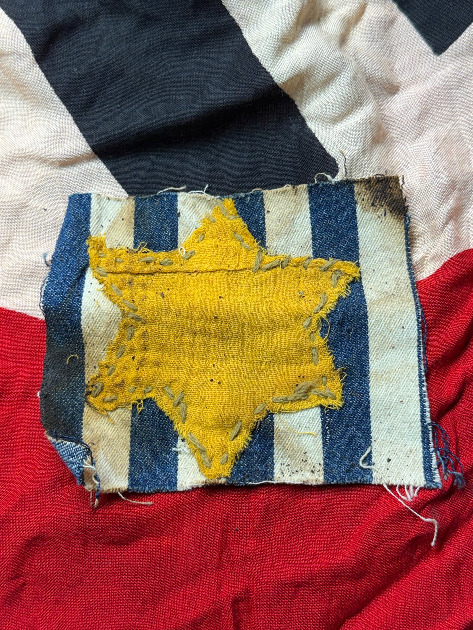 WW2 GERMAN CONCENTRATION CAMP UNIFORM STAR OF DAVID CUT OUT: This textile fragment is an Star of David identification badge, forcibly worn by Jews under Nazi rule during the Holocaust. Hand-cut from yellow cloth and crudely stitched onto a striped fabric backin