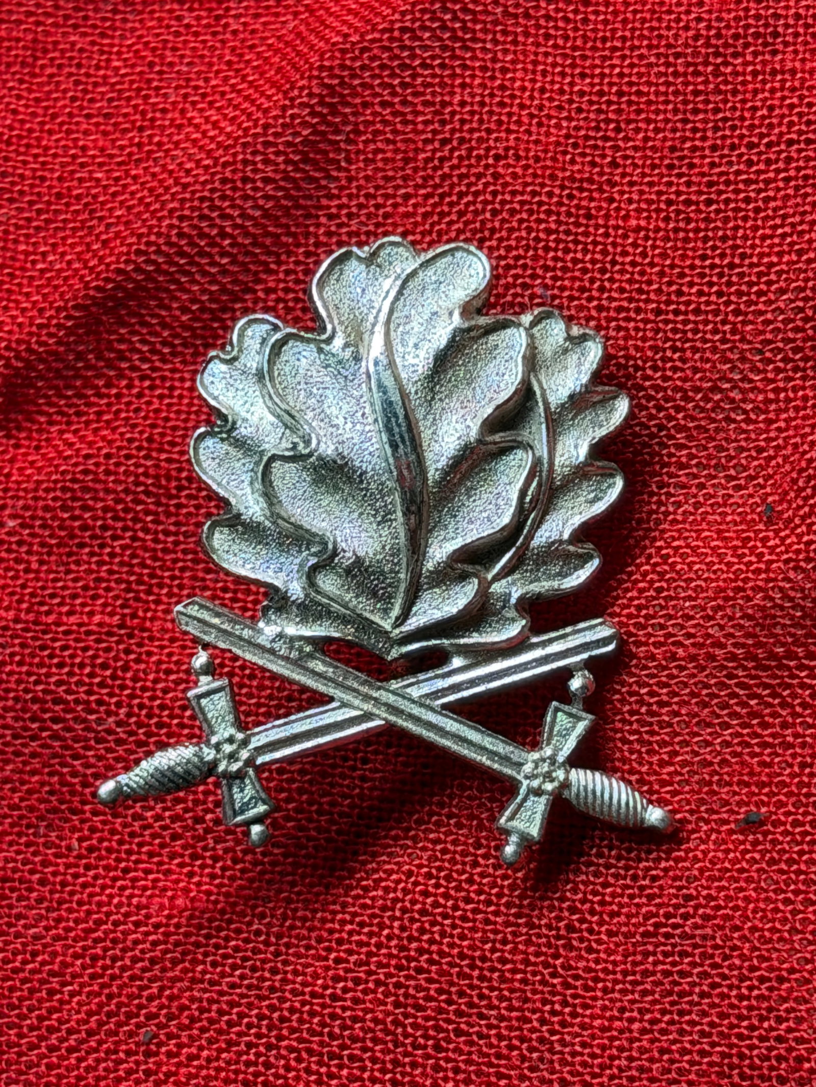 WW2 Wehrmacht Oak Leaves and Swords Device for the Knight’s Cross: This metal insignia is a Wehrmacht Oak Leaves and Swords device, awarded as an elevated distinction within the Knight’s Cross of the Iron Cross award hierarchy. The design features a stylized cluste