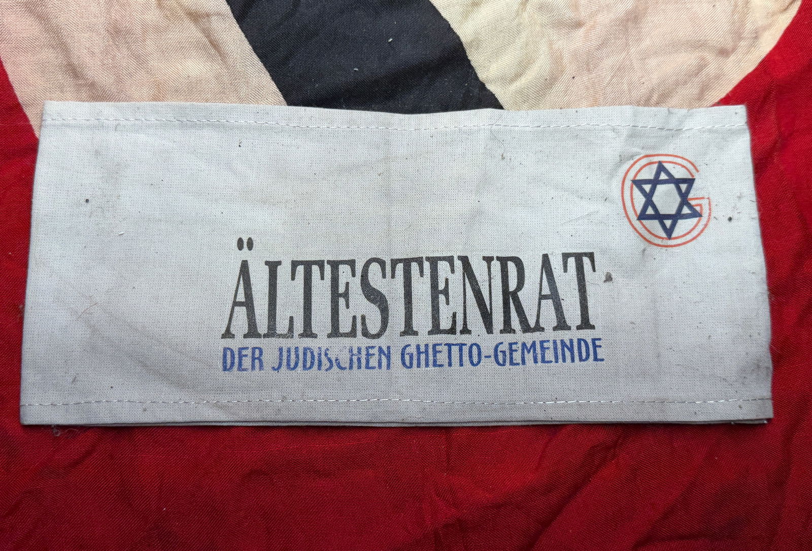 WW2 German Armband of the Jewish Ghetto Council (Ältestenrat): This cloth armband bears the printed inscription “Ältestenrat der jüdischen Ghetto-Gemeinde” (“Council of Elders of the Jewish Ghetto Community”) and a Star of David emblem, identify