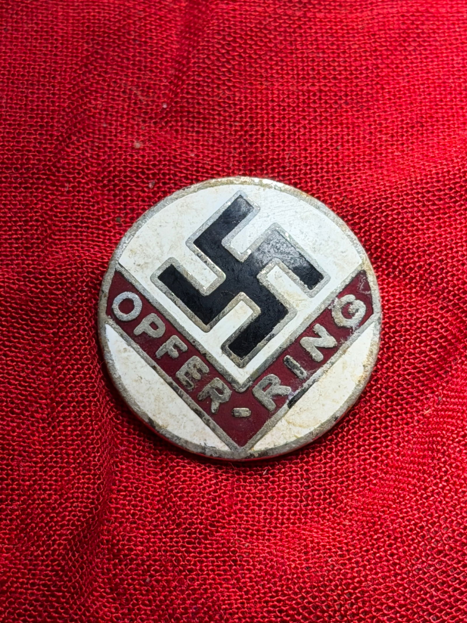 WW2 German NSDAP “Opfer-Ring?? Enamel Lapel Badge: NSDAP “Opfer-Ring” (Sacrifice Ring) badge, produced in Germany during the Third Reich period (1933–1945). The obverse displays a black swastika set within a white enamel field, bordered by a