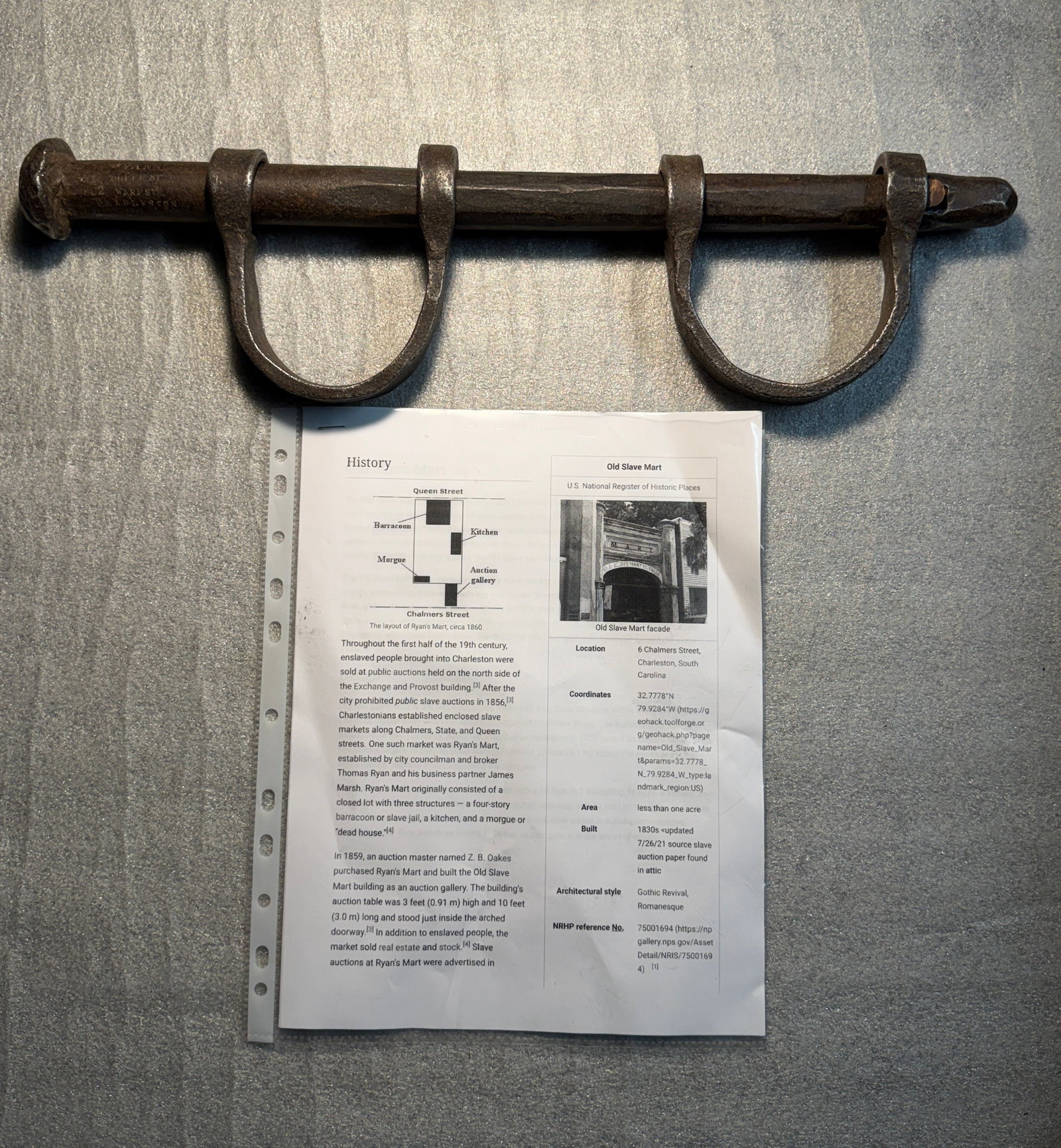 Slave Shackle Bar with Dual Wrist Irons, Marked “R. Ryan, 22 Warren Street, Charleston, South: This heavy iron restraint consists of a forged bar fitted with two fixed wrist shackles, an apparatus designed to immobilize and control the movement of enslaved people. Measuring approximately eighte