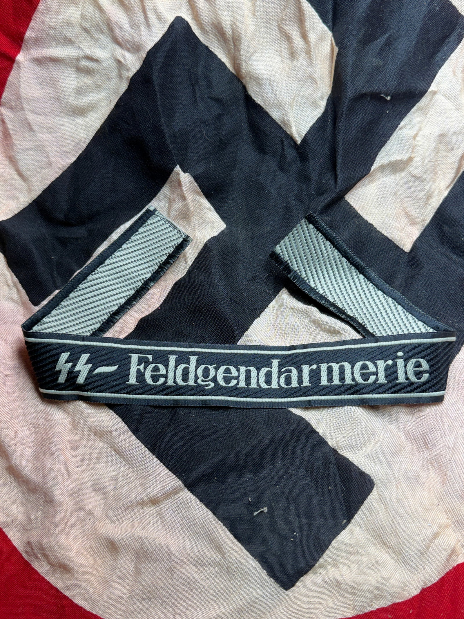 WW2 German Waffen SS-Feldgendarmerie Cuff Title (Ärmelstreifen): This textile artifact is an original SS-Feldgendarmerie cuff title (Ärmelstreifen), worn on the lower sleeve of the uniform to denote assignment and authority. Woven in dark blue fabric with light gr