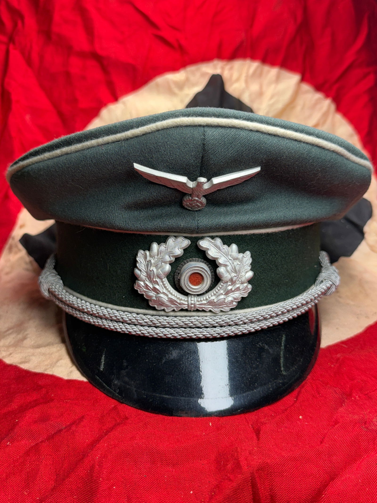 WW2 German Army (Heer) Officer’s Visor Cap (Schirmmütze), c. 1939–1945: This officer’s visor cap (Schirmmütze) is an example of headgear worn by commissioned officers of the German Army (Heer) during the Second World War. Constructed in field-gray wool with a dark gree