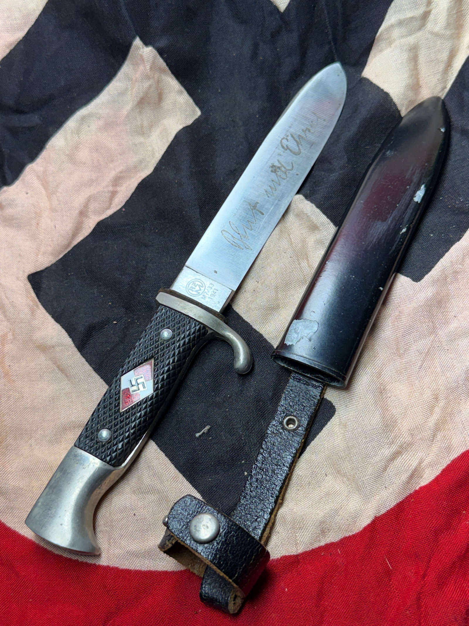 WW2 German Hitler Youth (HJ) Utility Knife with Inscribed Blade and Scabbard: This object is a standard-issue Hitler Youth (Hitlerjugend) knife, a symbolic and functional item issued to members of the Nazi Party’s youth organization in Germany prior to and during the Second W