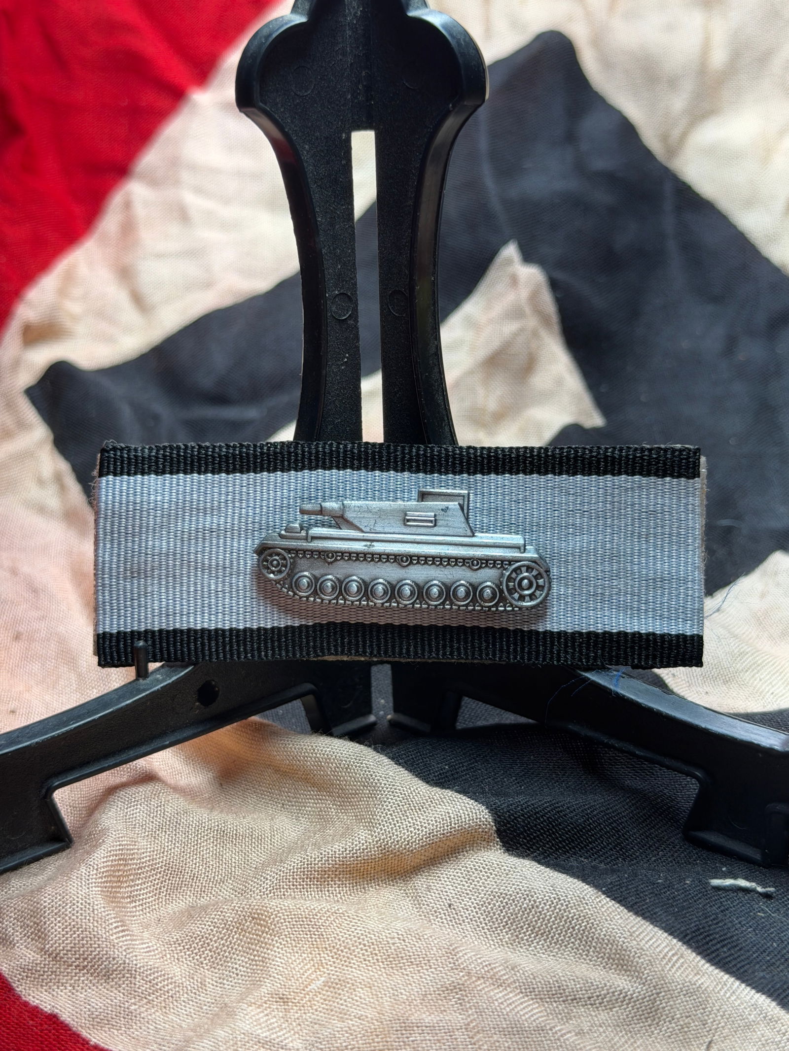 German Armored Assault Gun Proficiency Badge (Ribbon Bar Device), World War II: This artifact is a German military ribbon bar featuring a miniature metal device depicting a tracked armored assault gun, mounted on a gray ribbon with black edge stripes. Such ribbon bars were worn o
