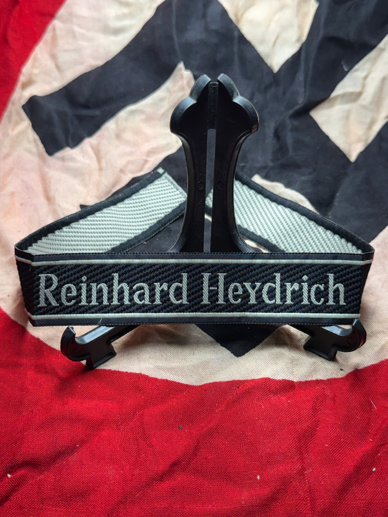 WW2 German Cuff Title “Reinhard Heydrich?? (Ärmelstreifen), Waffen-SS: This artifact is a German Waffen-SS cuff title (Ärmelstreifen) bearing the name “Reinhard Heydrich.” Woven in silver-gray thread on a black background, the cuff title was worn on the lower sl