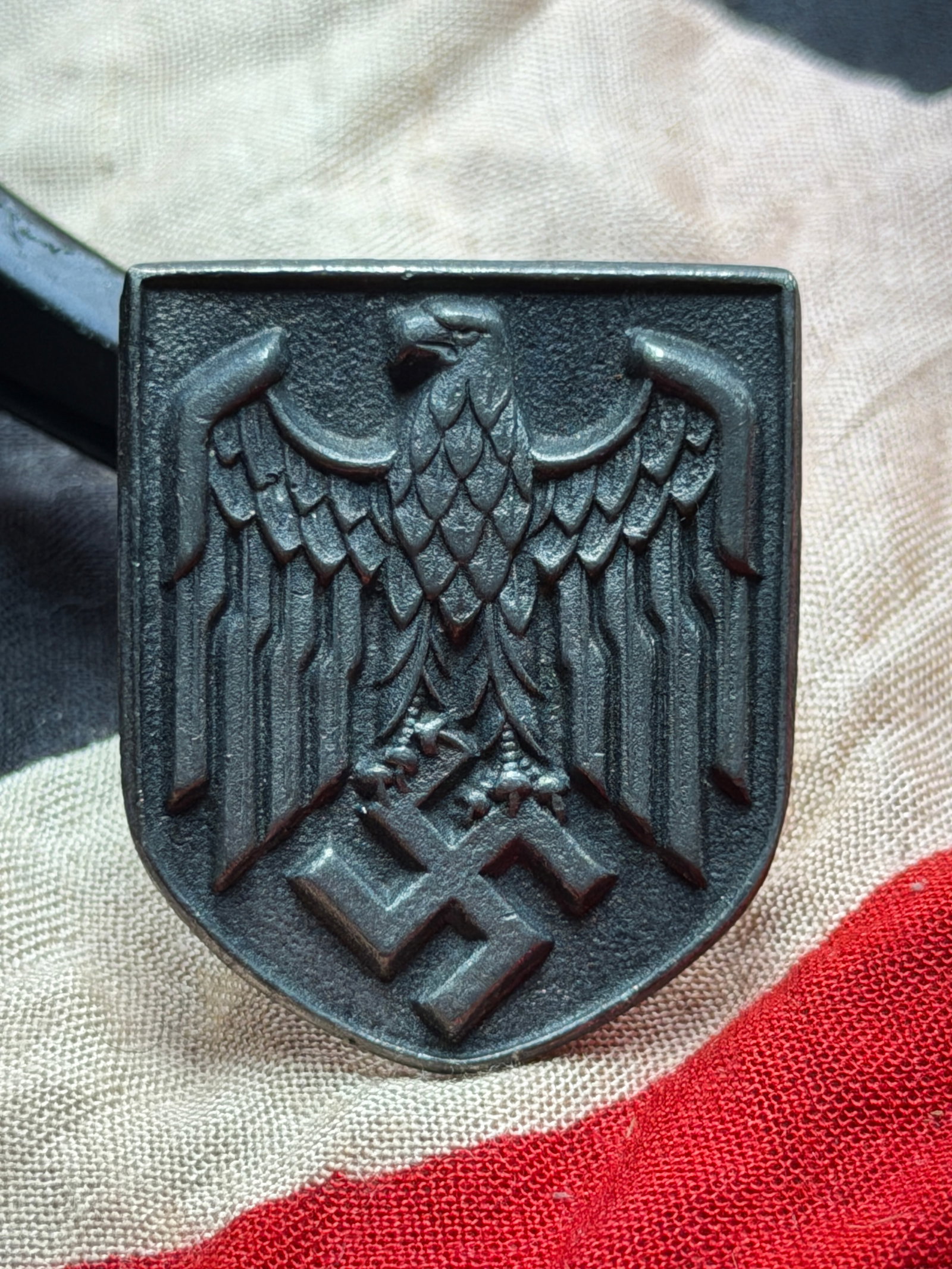 WW2 German Shield Plate from a German Pith Helmet (Tropenhelm): This metal shield plate is identified as a front insignia from a German Tropenhelm (pith helmet) used during the Second World War. Featuring a stylized national eagle above a centrally placed swastika