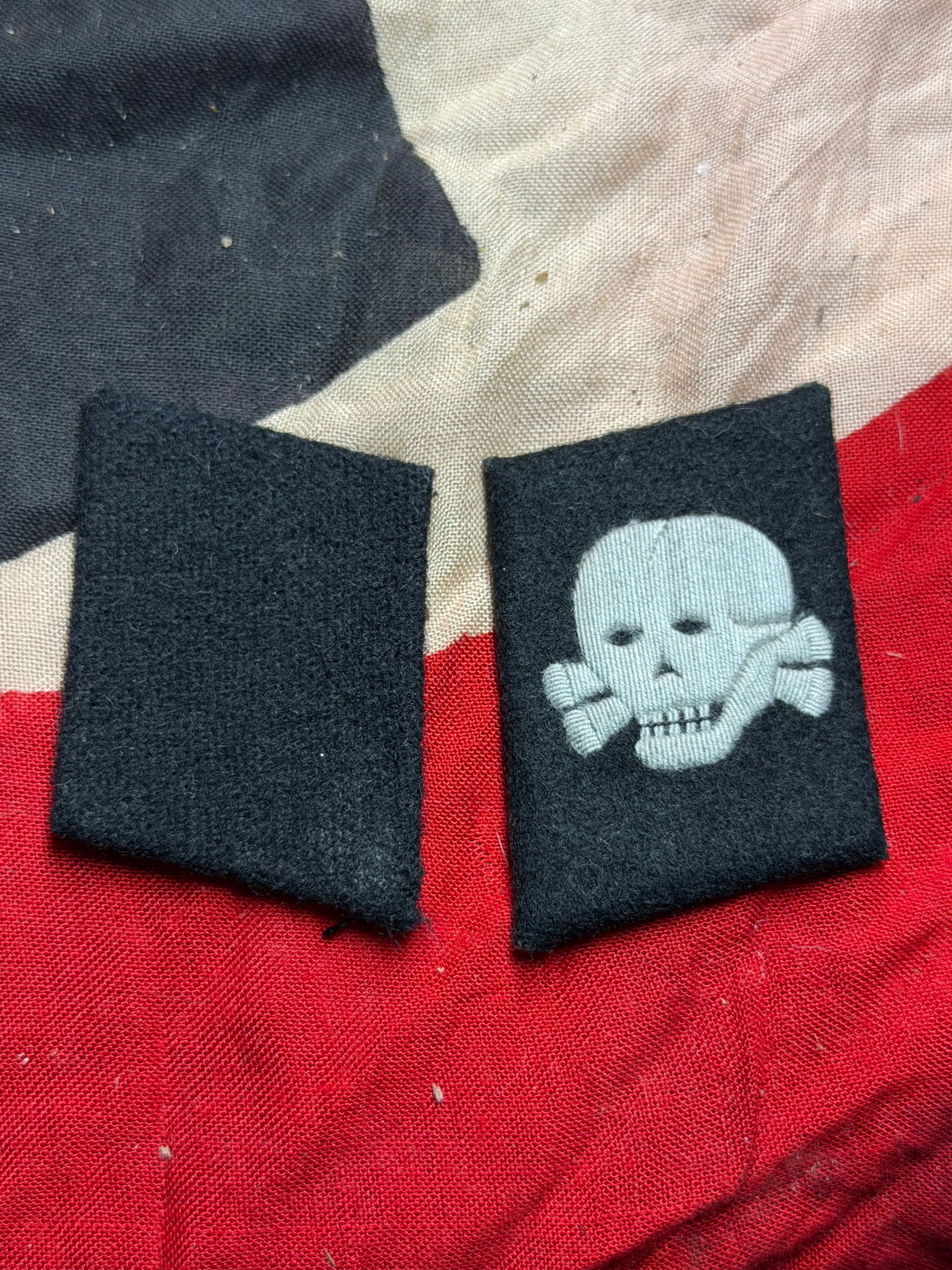 WW2 German Waffen-SS Collar Tabs with Totenkopf Insignia: This matched pair of black wool collar tabs is associated with the Waffen-SS, the armed wing of the Schutzstaffel in Nazi Germany during the Second World War. One tab bears the embroidered Totenkopf (