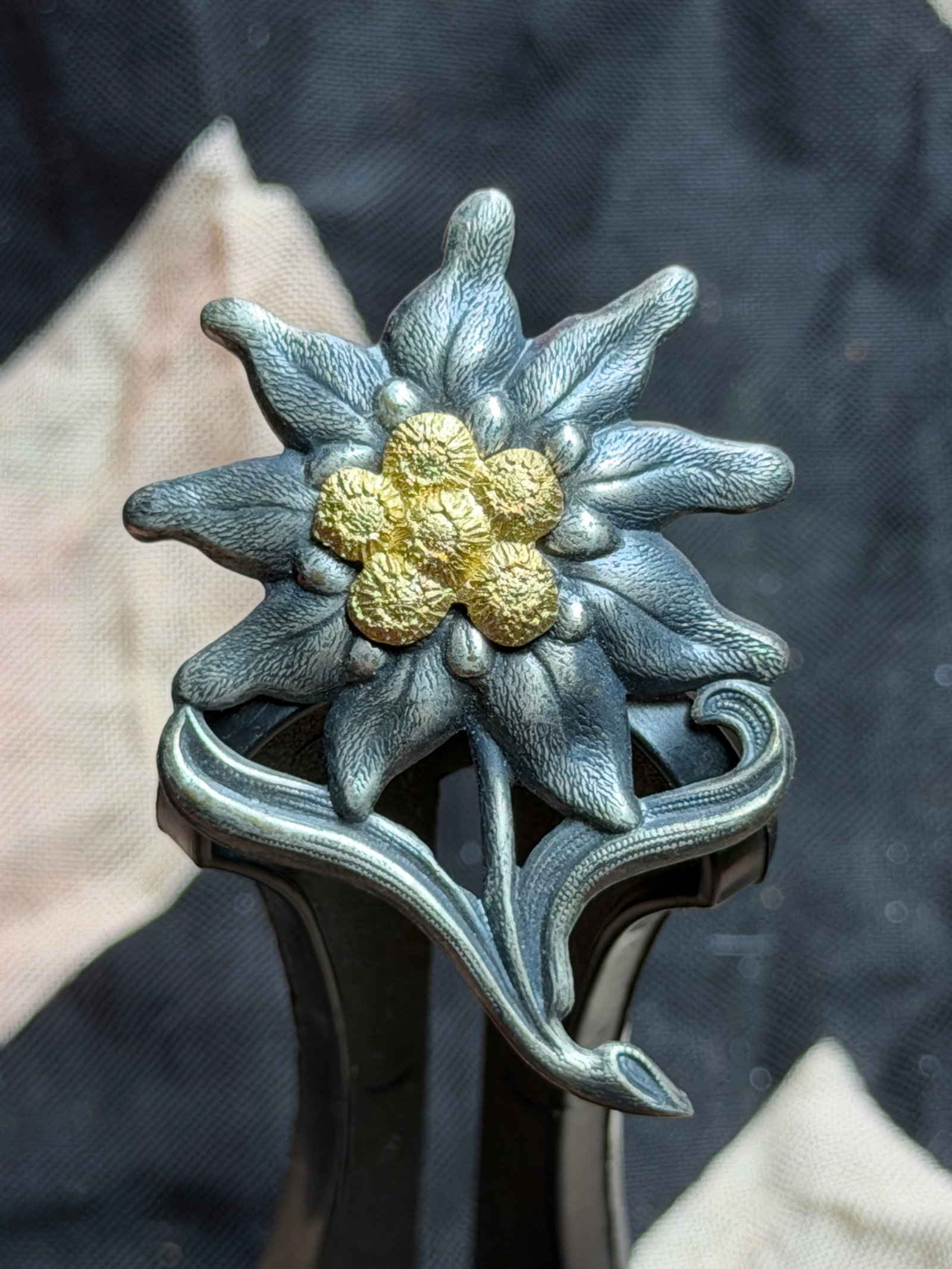 WW2 German Edelweiss Cap Badge (Gebirgsjäger Insignia): This metal Edelweiss badge represents the emblem traditionally worn by German mountain troops (Gebirgsjäger). The Edelweiss flower, a hardy alpine plant native to high-altitude regions, was adopted a