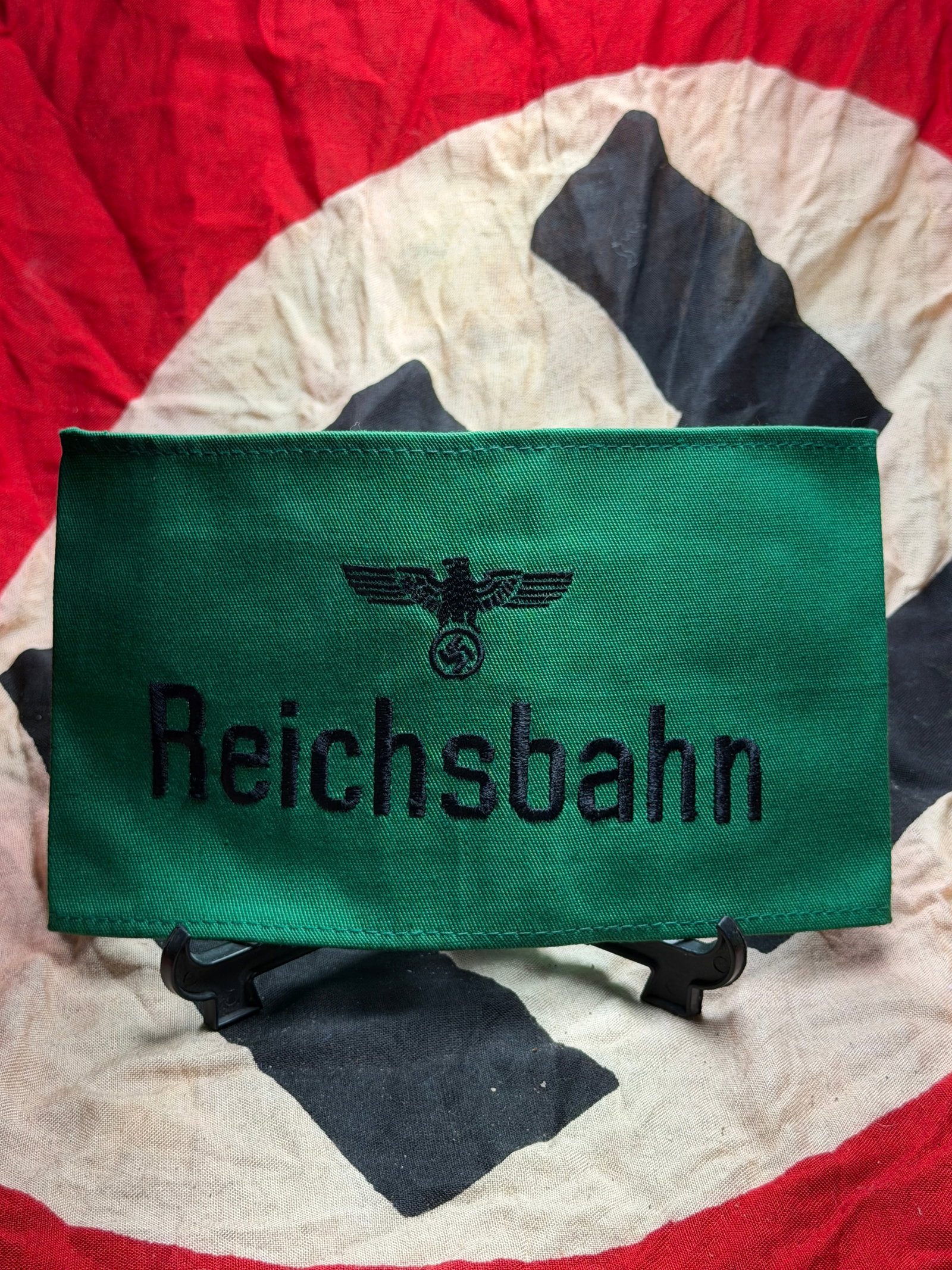 WW2 German Armband Insignia of a Reichsbahn: This green armband bears the black embroidered inscription “Reichsbahn” beneath the national eagle emblem of Nazi Germany, identifying its wearer as an official or employee of the Deutsche Rei