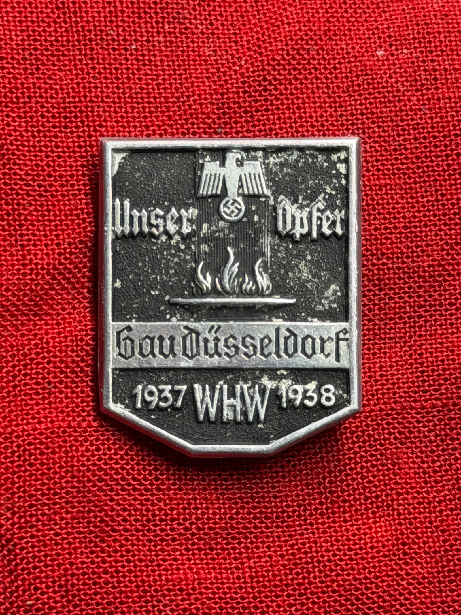 WW2 German Winterhilfswerk (WHW) Donation Badge, Düsseldorf Construction Campaign, 1937–1938: This small metal badge is a Winterhilfswerk des Deutschen Volkes (Winter Relief of the German People, WHW) donation badge, issued during the 1937–1938 winter campaign in Düsseldorf. The Winterhilfs