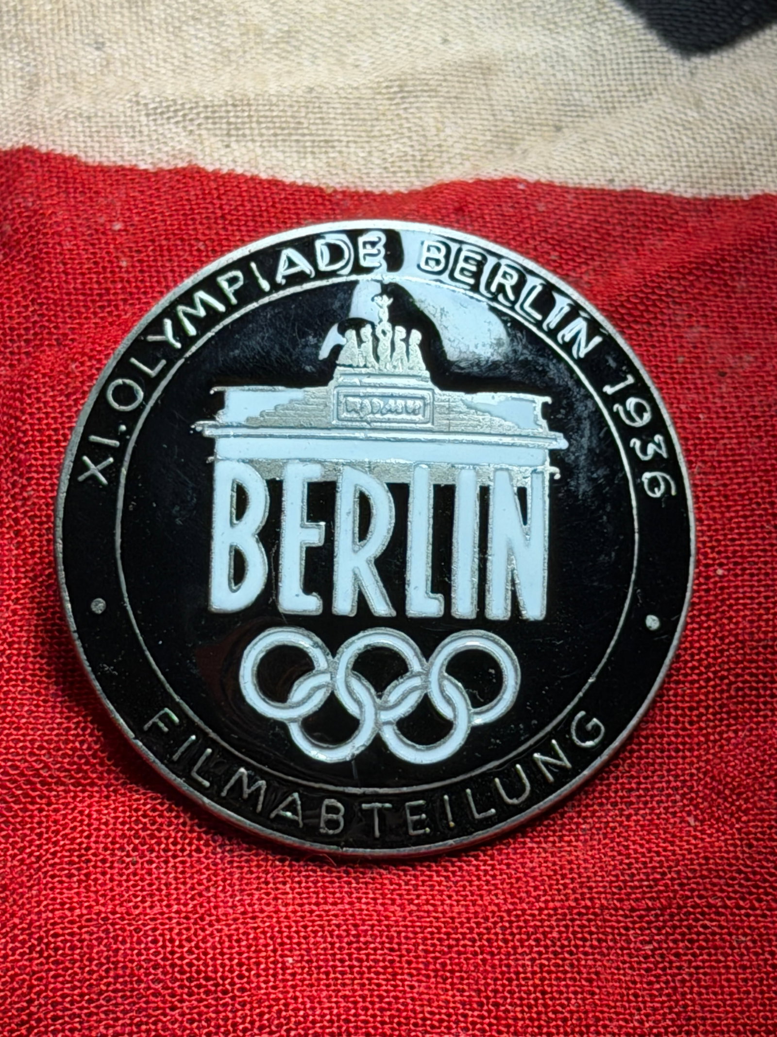 WW2 German Participant Badge, XI Olympic Games, Berlin 1936: This circular metal badge was issued to accredited participants of the XI Olympic Games held in Berlin in 1936. The obverse features the Brandenburg Gate above the word BERLIN, paired with the Olympic