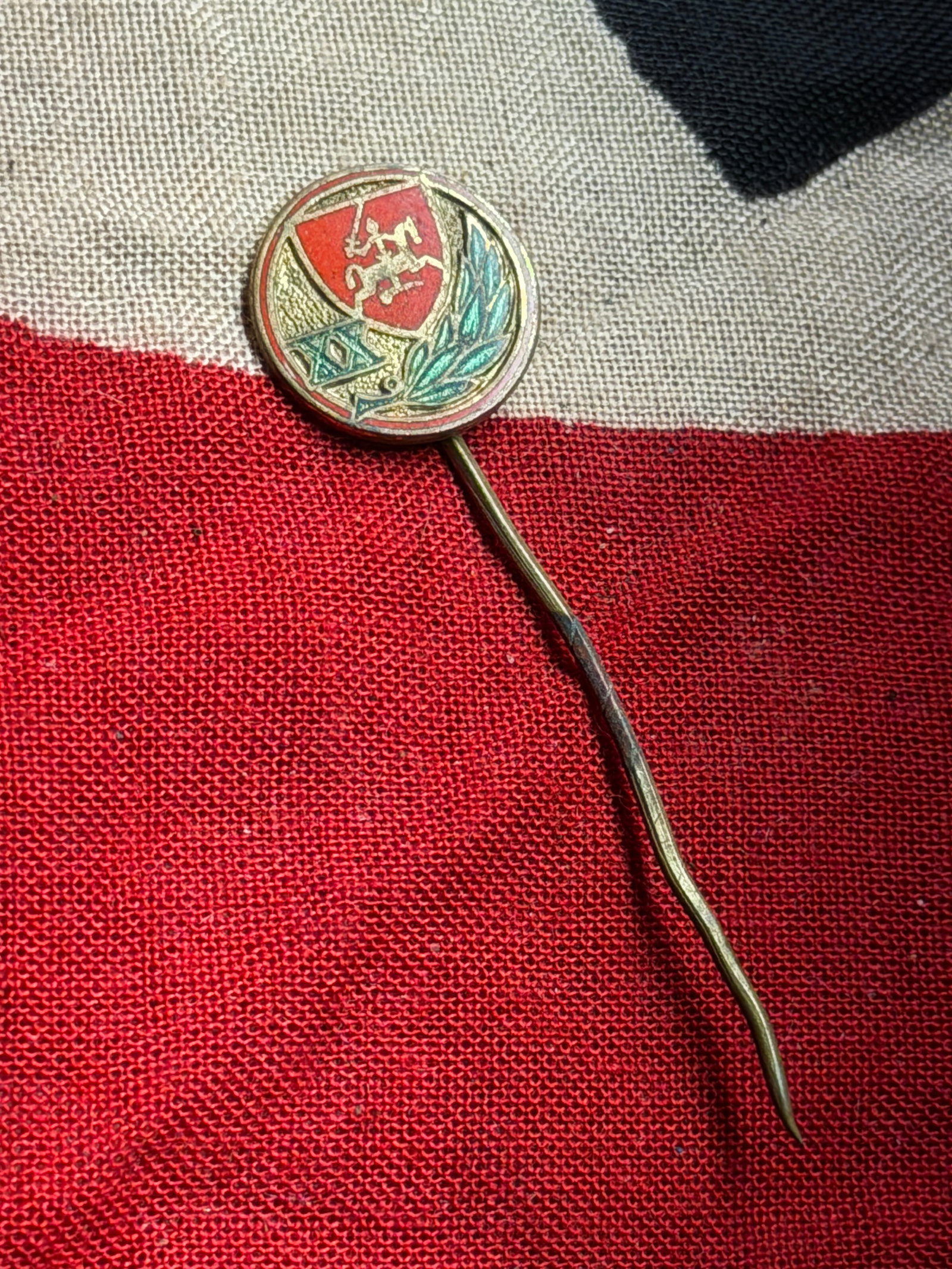 German Veterans’ Association Stick Pin with Heraldic Emblem, Interwar Period, c. 1919–1933: This enameled stick pin is a German veterans’ association badge from the interwar period following the First World War. Designed for civilian wear, the pin features a circular medallion with a quart