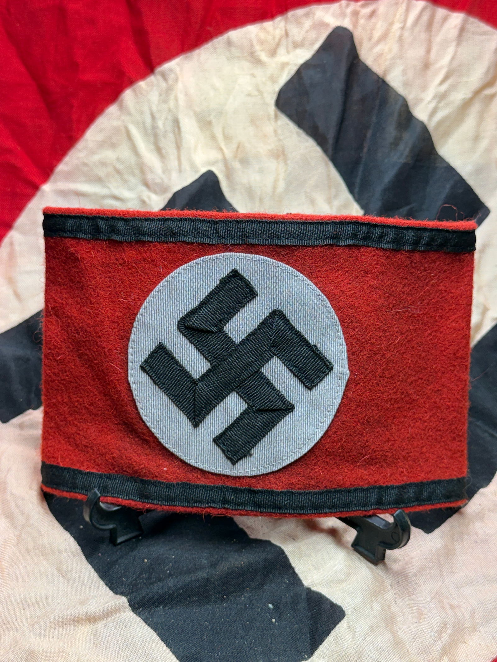 WW2 German Armband of the National Socialist German Workers’ Party (NSDAP): This wool armband bears the emblem of the National Socialist German Workers’ Party (NSDAP), consisting of a black swastika appliqué set within a white roundel on a red field. Such armbands were amo