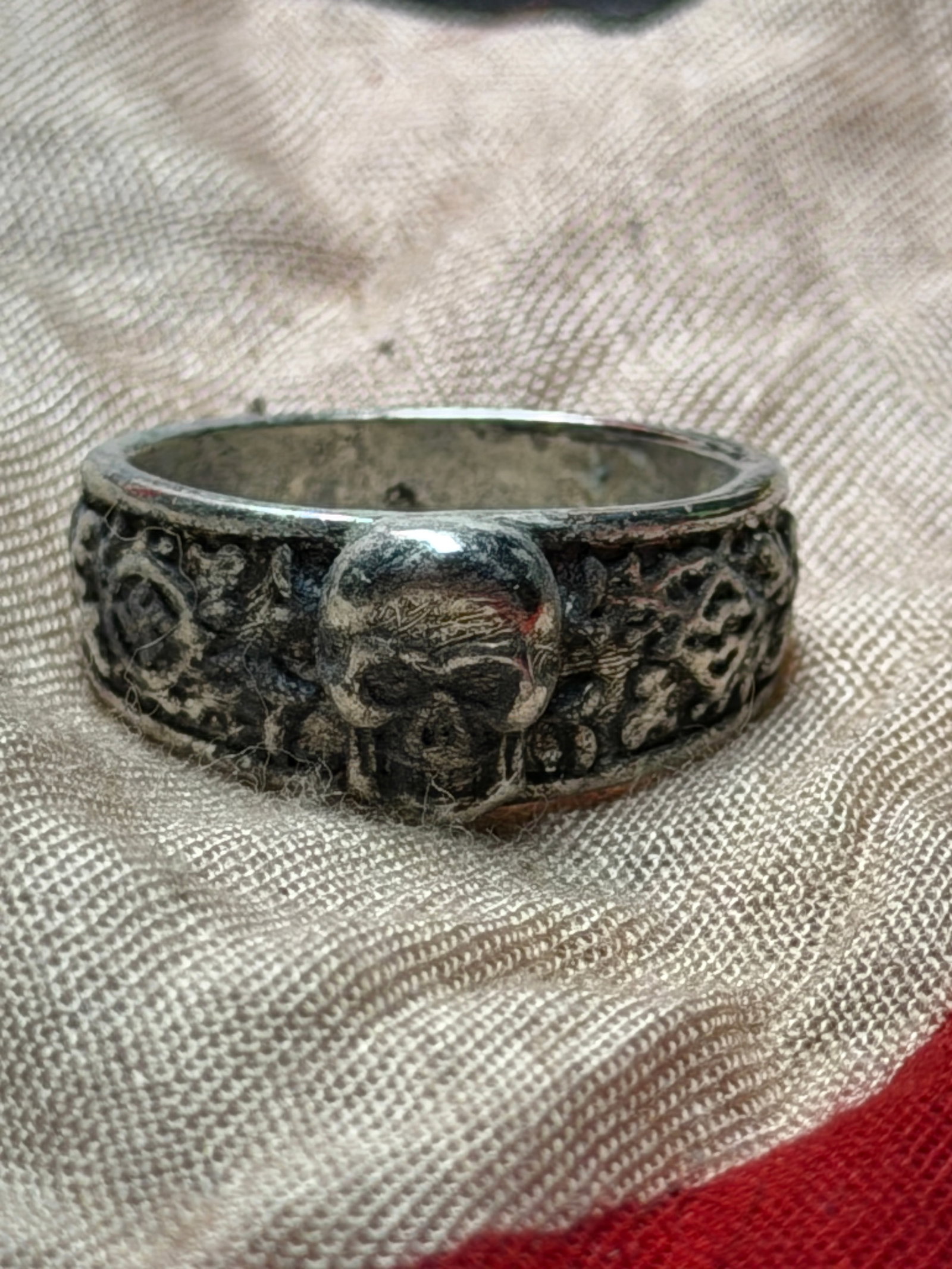 WW2 German Ring with Skull Motif (Totenkopf Ring): This metal ring features a raised skull motif at the center, flanked by a heavily textured band with organic, relief-like decoration. The skull—long a symbol in European military and fraternal tradi