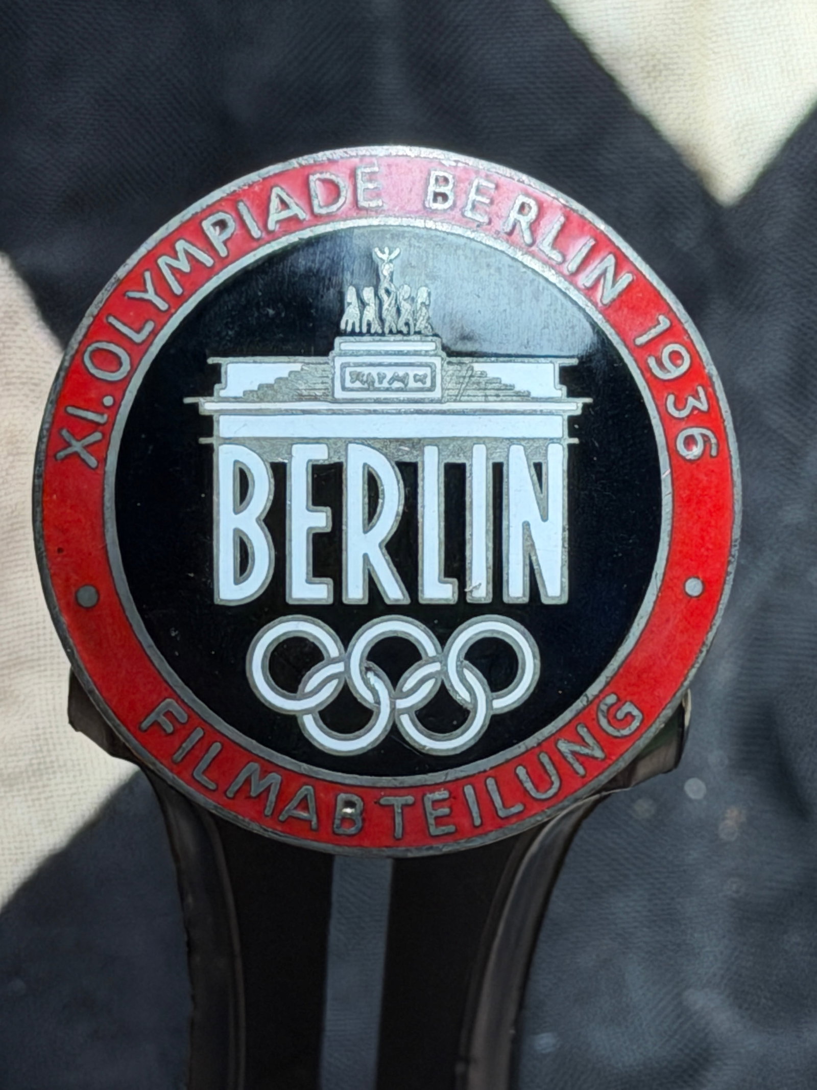 WW2 German 1936 Berlin Olympic Games Film Department Badge (XI. Olympiade Berlin 1936): This specifically marked “Filmartbeilung” (Film Department), identifying it as an accreditation or identification badge for personnel involved in official Olympic film production. The obverse 