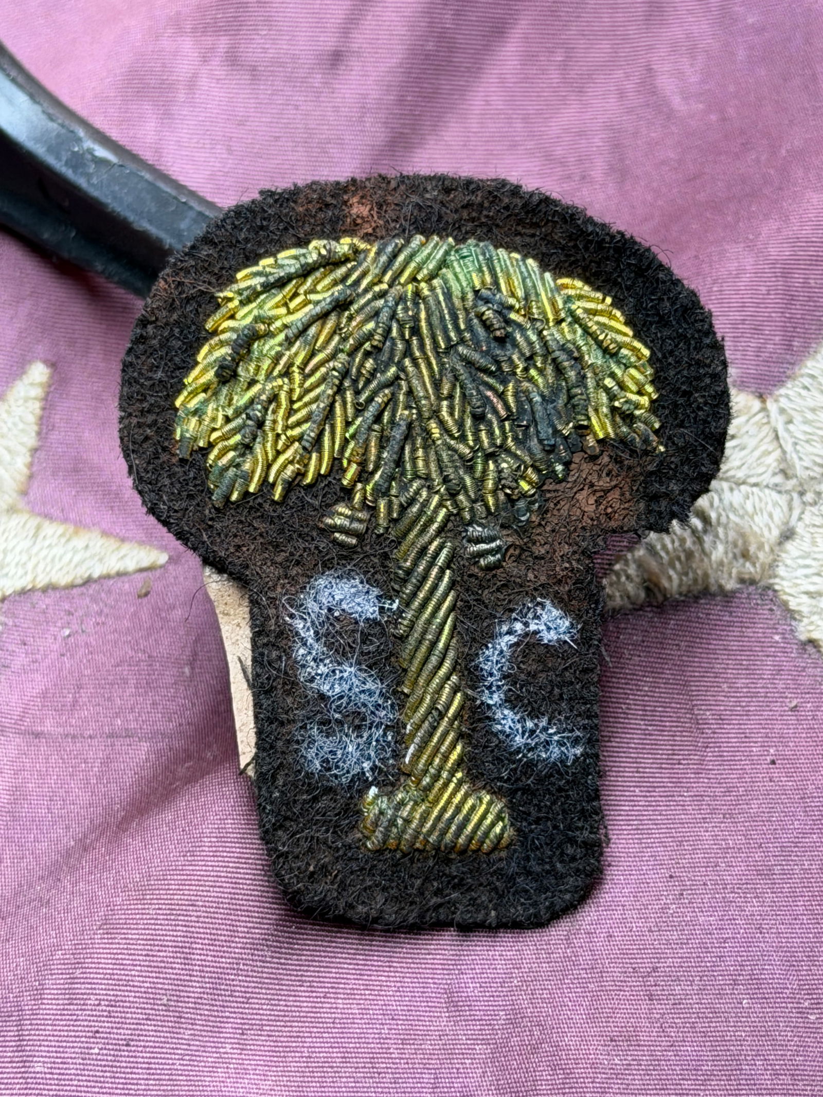 South Carolina Officer’s Bullion Insignia, American Civil War Era (1861–1865) By J.H. Silverberg: This hand-embroidered bullion insignia represents South Carolina military service during the American Civil War. Constructed of coiled gold bullion wire stitched onto a dark wool backing, the device f