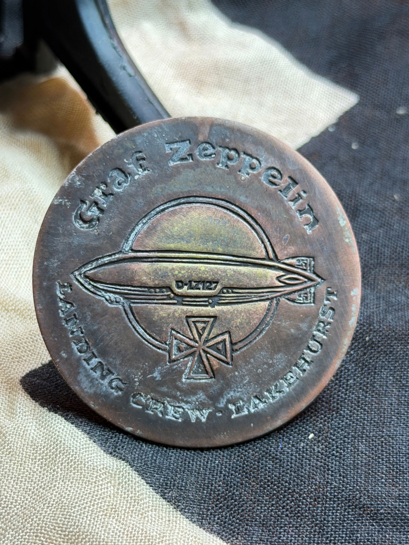 WW2 Commemorative Badge of the German Airship “Graf Zeppelin: This circular metal badge commemorates the German rigid airship Graf Zeppelin (LZ-127), one of the most famous dirigibles of the interwar period. The obverse features a stylized side profile of the ai