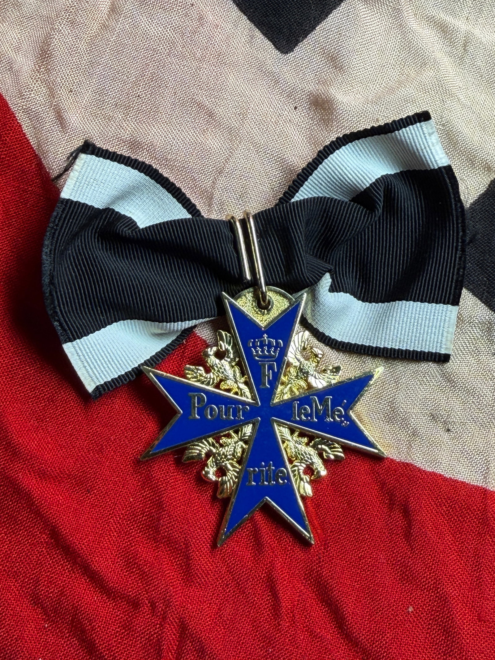 WW2 German Pour le Mérite Order Insignia with Bow Ribbon: This object is a gilt and enamel insignia of the Pour le Mérite, a historic order of merit originally established in the Kingdom of Prussia in the 18th century. The decoration consists of a blue enam