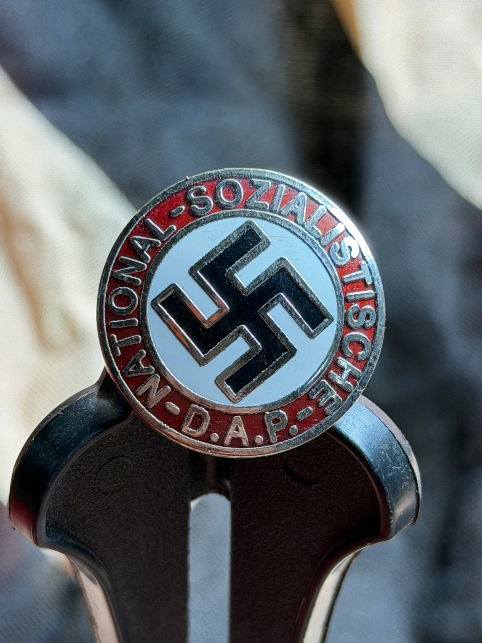 WW2 National Socialist German Workers’ Party (NSDAP) Membership Badge: This circular enamel badge is associated with the National Socialist German Workers’ Party (NSDAP) in Germany during the interwar and Second World War periods. The obverse features a black swastika