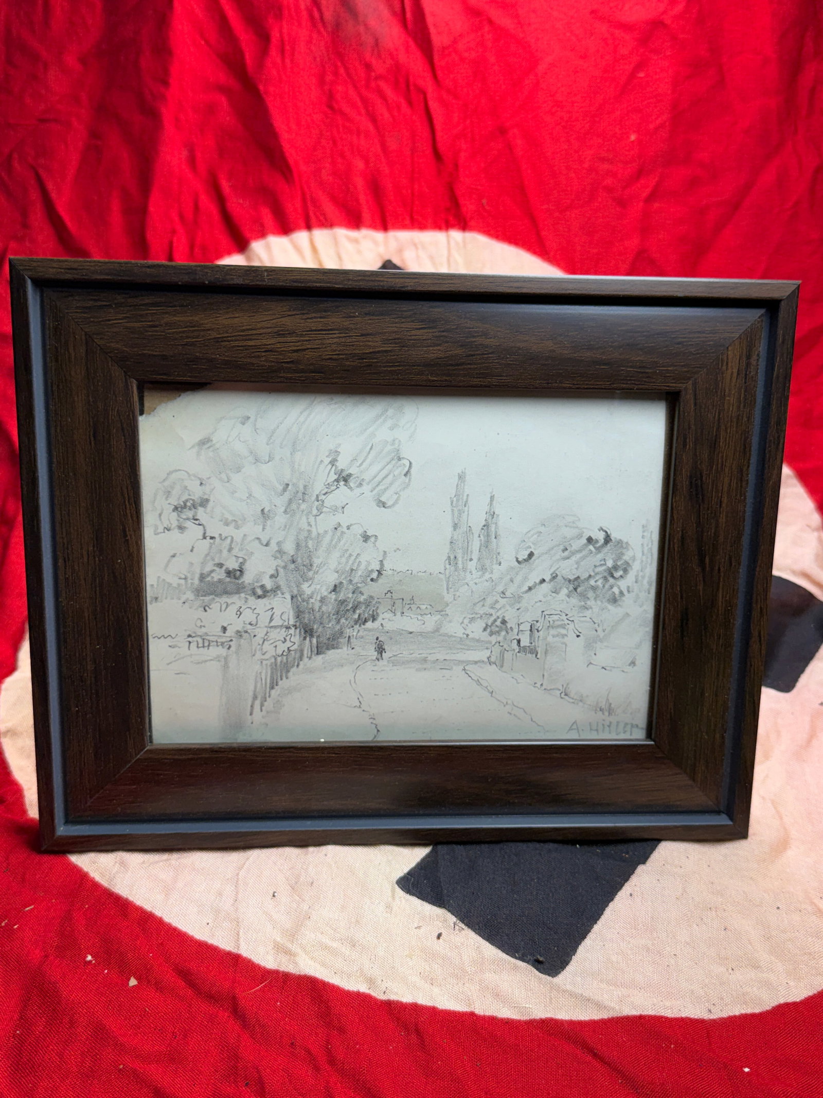 WW2 German Pencil Landscape Drawing By Adolf Hitler, Signed “A. Hitler: This small graphite drawing depicts a quiet, tree-lined roadway leading toward a distant Gothic cathedral with twin spires. Executed in a loose, sketch-like style, the composition emphasizes atmospher