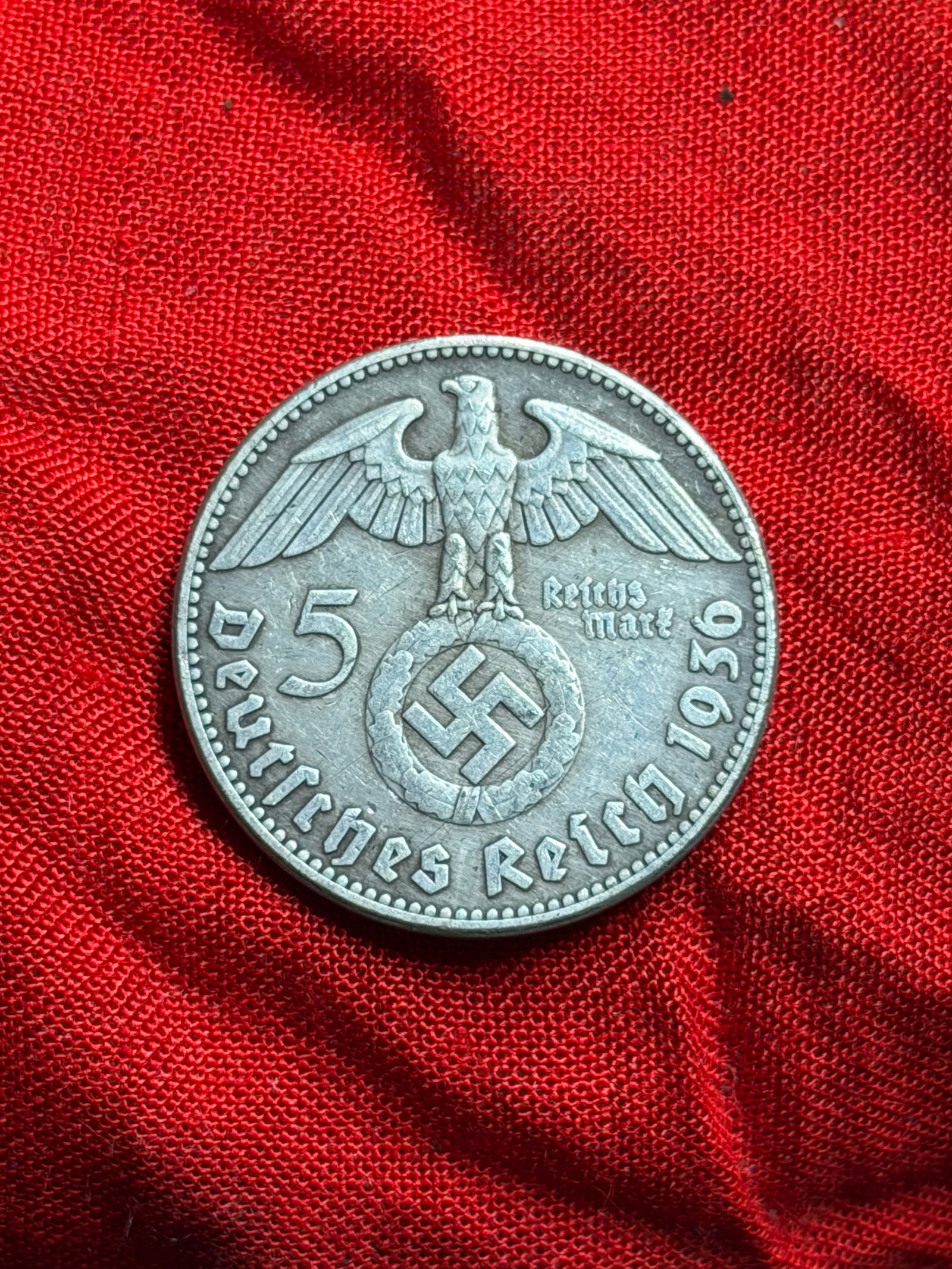 WW2 German 5 Reichsmark Coin with Portrait of Paul von Hindenburg: This silver coin is a 5 Reichsmark piece issued by the German Reich during the National Socialist period , dated 1936–1939 . The obverse features a right-facing portrait of Paul von Hindenburg , Pre