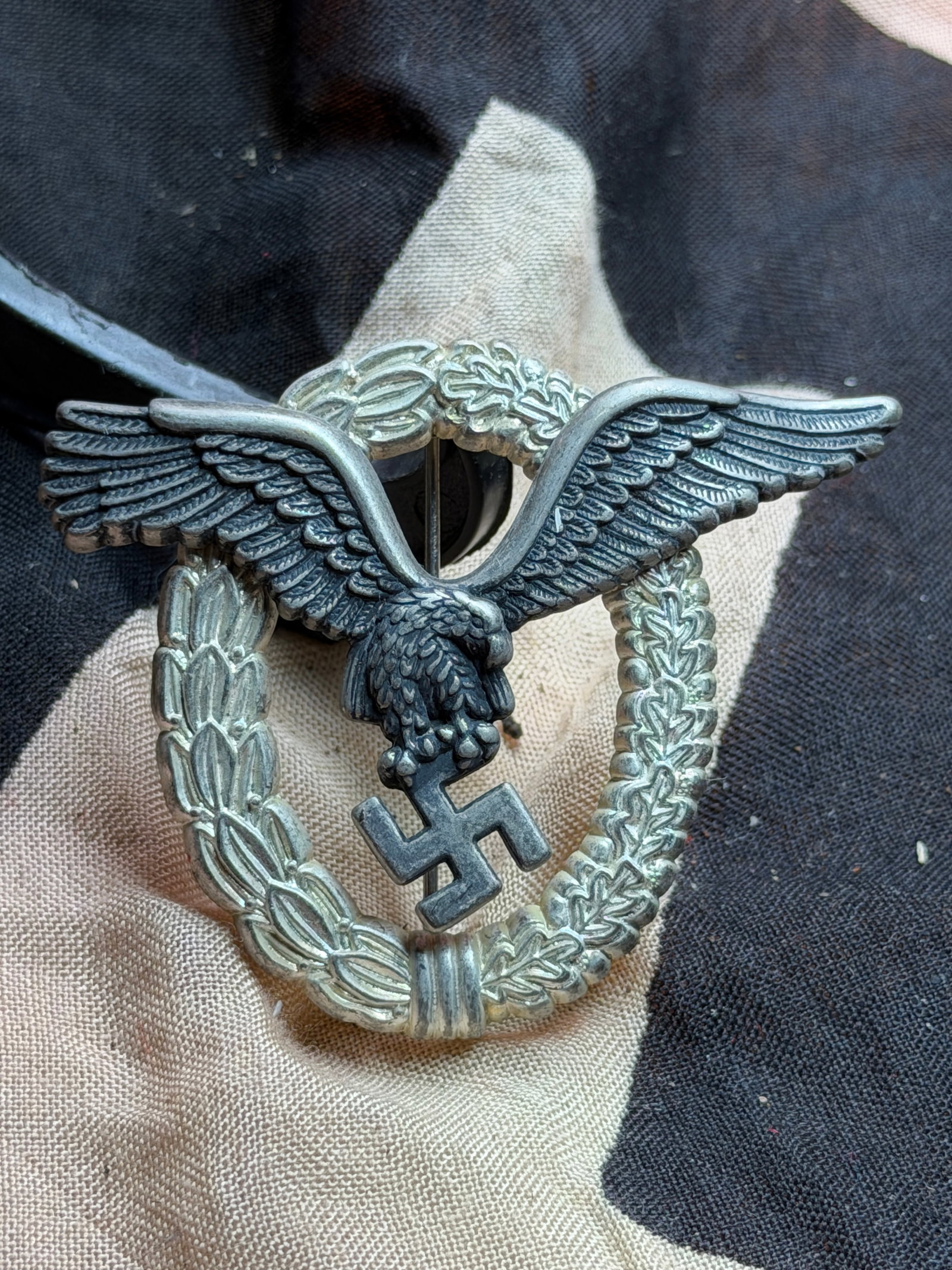 WW2 Luftwaffe Pilot’s Badge (Flugzeugführerabzeichen),: This metal insignia is a German Luftwaffe Pilot’s Badge (Flugzeugführerabzeichen) , produced during the Second World War (c. 1939–1945) . The badge consists of a wreath of laurel and oak leaves ,