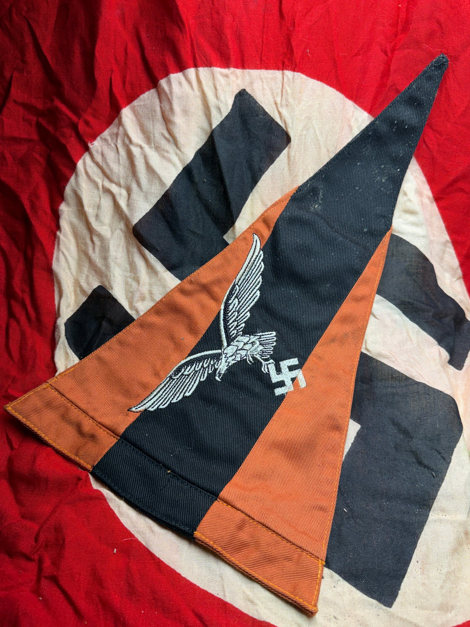 WW2 Luftwaffe Eagle Pennant (Vehicle or Signal Flag): This triangular pennant features the Luftwaffe national eagle clutching a swastika, embroidered in light gray thread on a black field, bordered by orange-brown panels. The color scheme and insignia ar