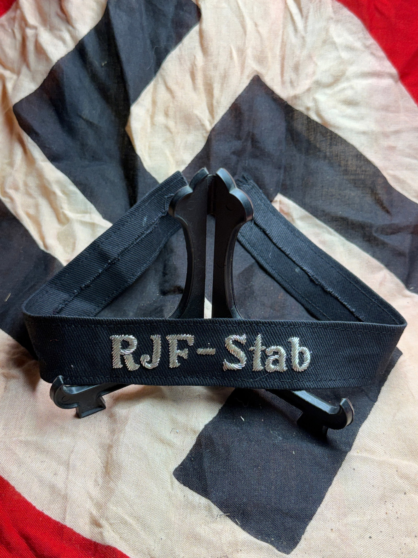 WW2 “RJF–Stab?? Armband with Plastic Clasp Assembly: This object is a black armband bearing the embroidered inscription “RJF–Stab” , referring to the Reichsjugendführung (Reich Youth Leadership), the central administrative staff of the Hitler