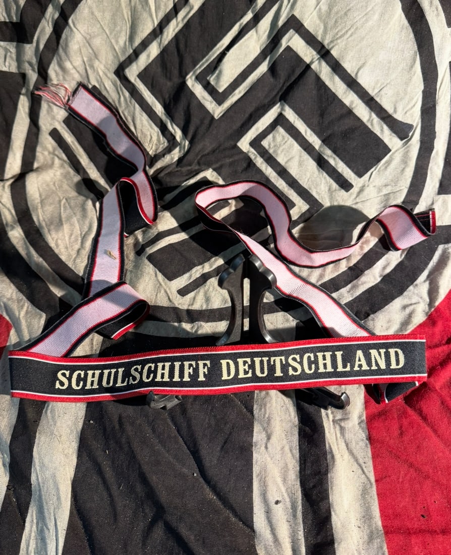 WW2 German Cap Tally of the German Training Ship Schulschiff Deutschland: This woven cap tally bears the inscription “Schulschiff Deutschland” (“Training Ship Germany”) and was worn on the sailor’s cap by cadets and trainees assigned to the German naval tr