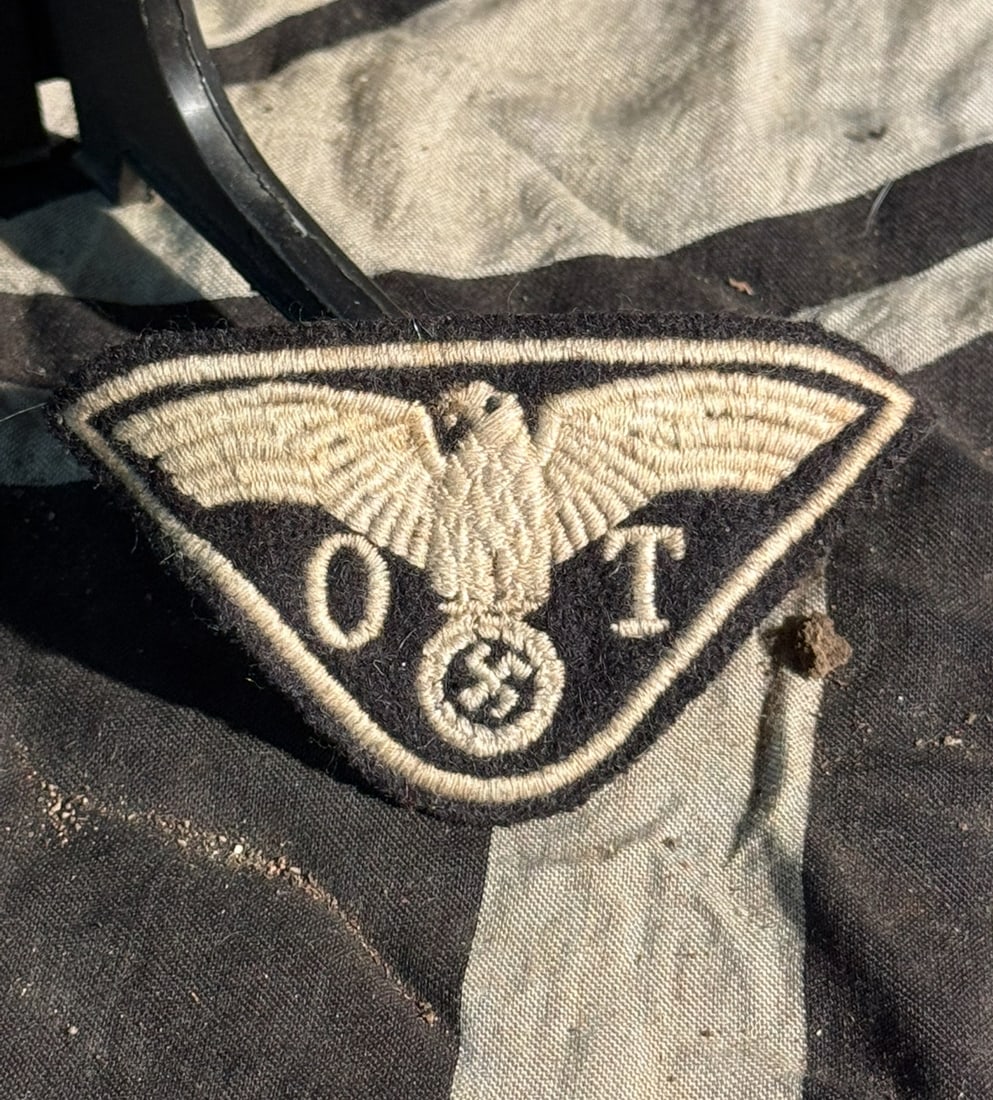 WW2 German Organisation Todt (OT) Sleeve Insignia: This embroidered cloth insignia is a sleeve patch associated with the Organisation Todt (OT), the Nazi Germany state-run engineering and construction organization active from 1938 to 1945. The triangu