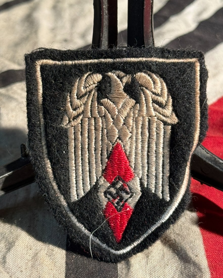 WW2 German Hitler Youth (Hitlerjugend) Standard Bearer’s Arm Shield With RZM Paper Tag: This cloth arm shield is identified as a Hitler Youth (Hitlerjugend) Standard Bearer’s arm shield, worn by members tasked with carrying unit flags and banners during parades, rallies, and official c