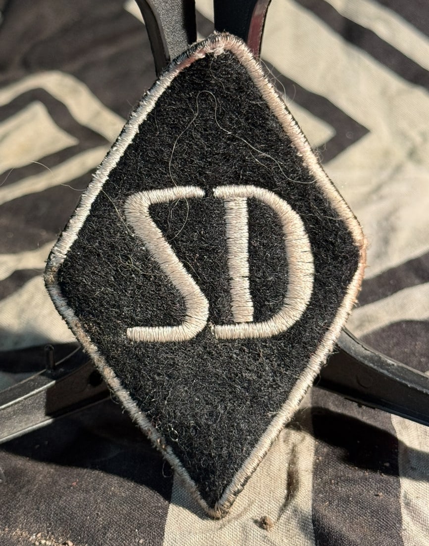 WW2 German SS–SD (Sicherheitsdienst) Sleeve Diamond Insignia With RZM Paper Tag: This embroidered cloth insignia is an SS–SD (Sicherheitsdienst) sleeve diamond, worn by members of the Security Service of the SS in Nazi Germany during World War II (c. 1939–1945). has the RZM pa
