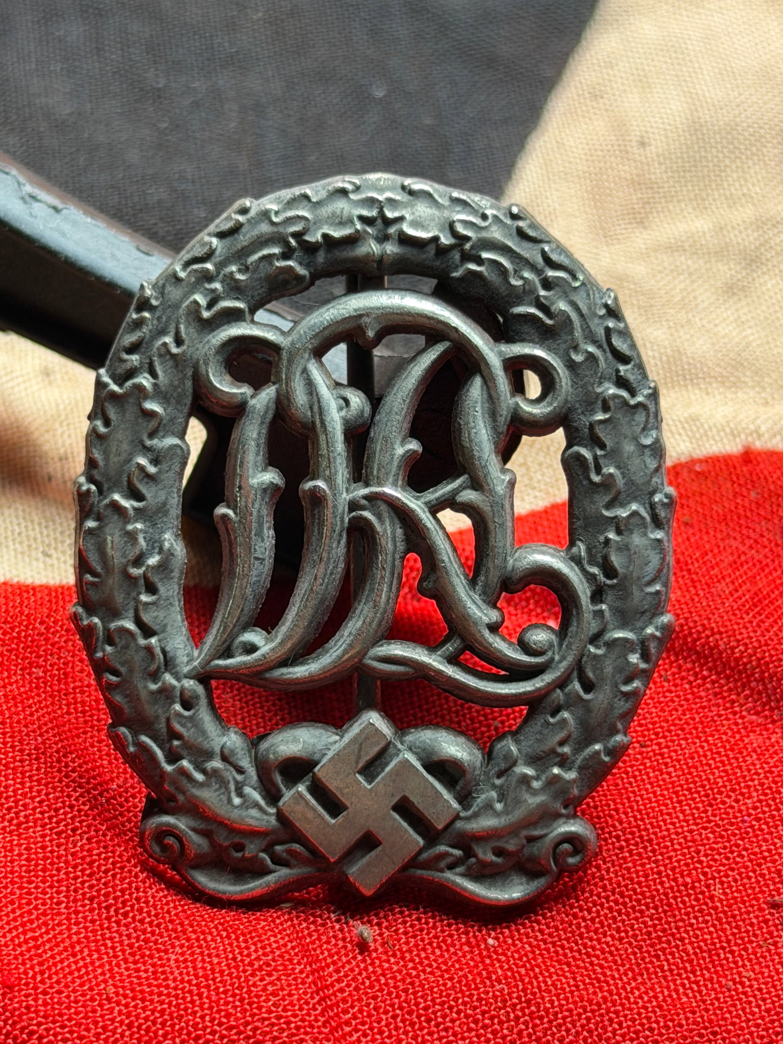 WW2 German National Sports Badge (Deutsches Reichssportabzeichen / DRL Badge): This metal badge is a German National Sports Badge, officially known as the Deutsches Reichssportabzeichen (DRL), awarded during the Nazi Germany period. Instituted to promote physical fitness, endura