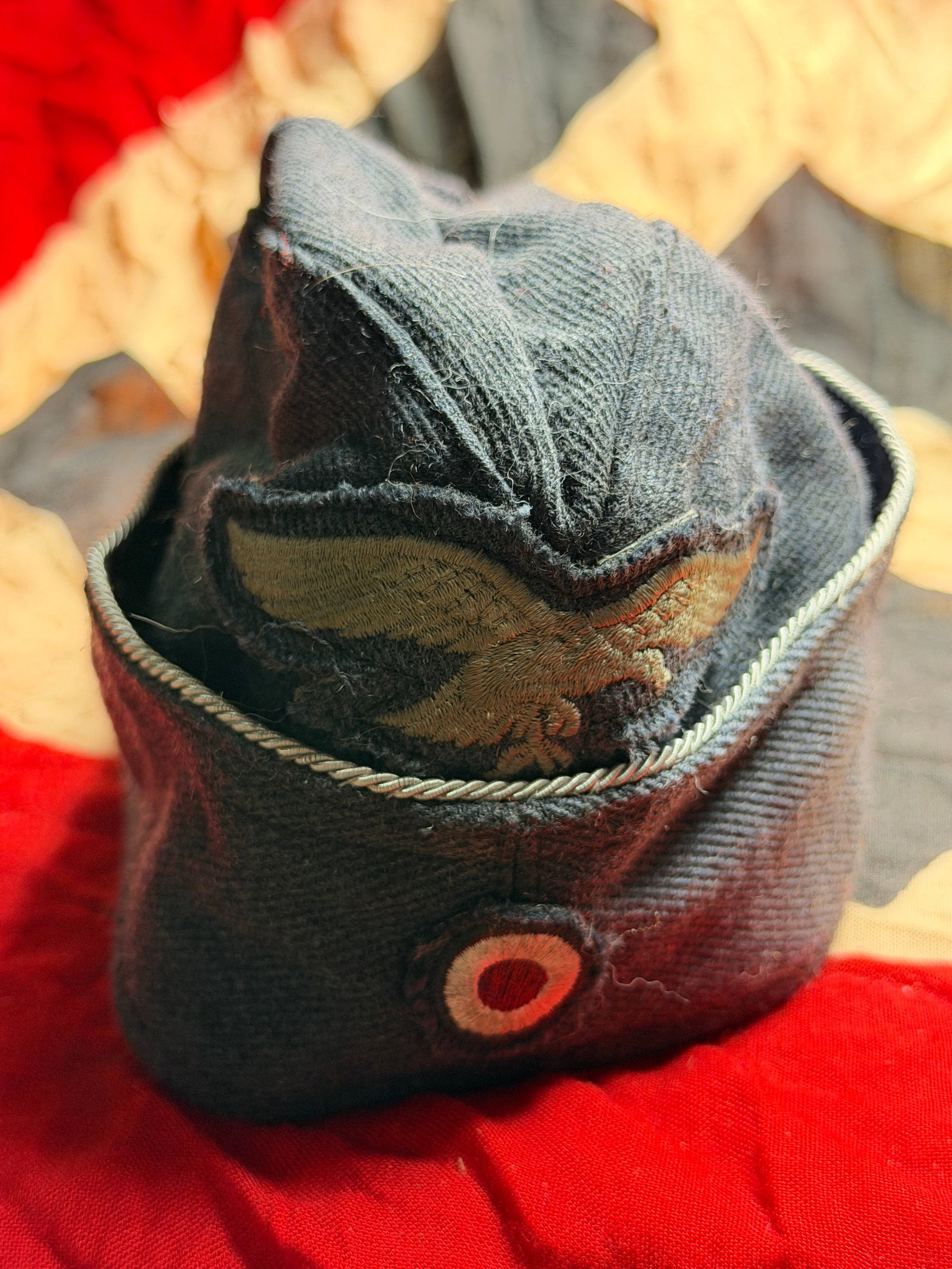 WW2 German Luftwaffe Officer’s Overseas Cap (Schiffchen): This German Luftwaffe officer’s overseas cap, known as a Schiffchen, dates to the Second World War. Tailored from blue-gray Luftwaffe wool, the cap features silver bullion piping along the crown sea