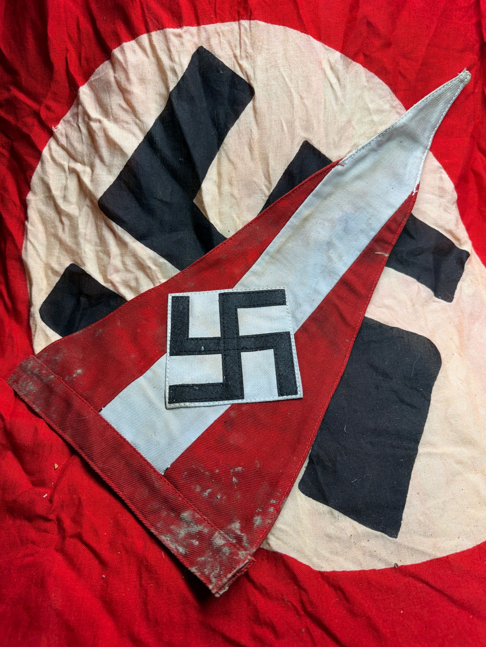 WW2 German Nazi Party Vehicle Pennant (NSDAP Insignia): This triangular vehicle pennant bears the emblem of the National Socialist German Workers’ Party (NSDAP), featuring a black swastika on a white field set within a red border. Such pennants were comm