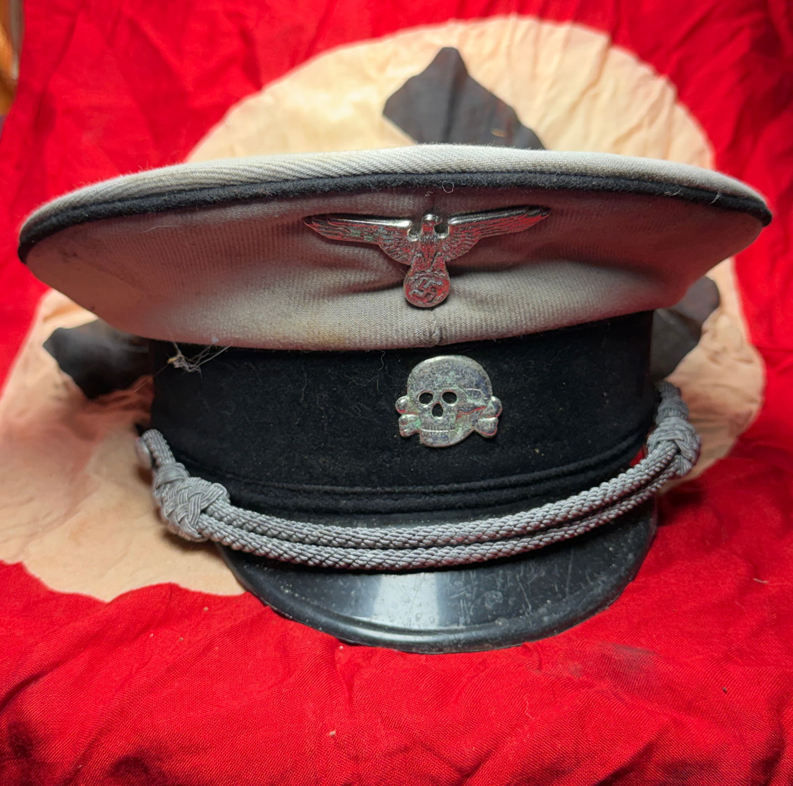 German WWII SS Officer Visor Cap (Schirmmütze) with Totenkopf Insignia, c. 1935–1939: This visor cap (Schirmmütze) is an original World War II–era example worn by an officer of the German Schutzstaffel (SS). Constructed of light-colored wool with a black velvet cap band, the cap fea