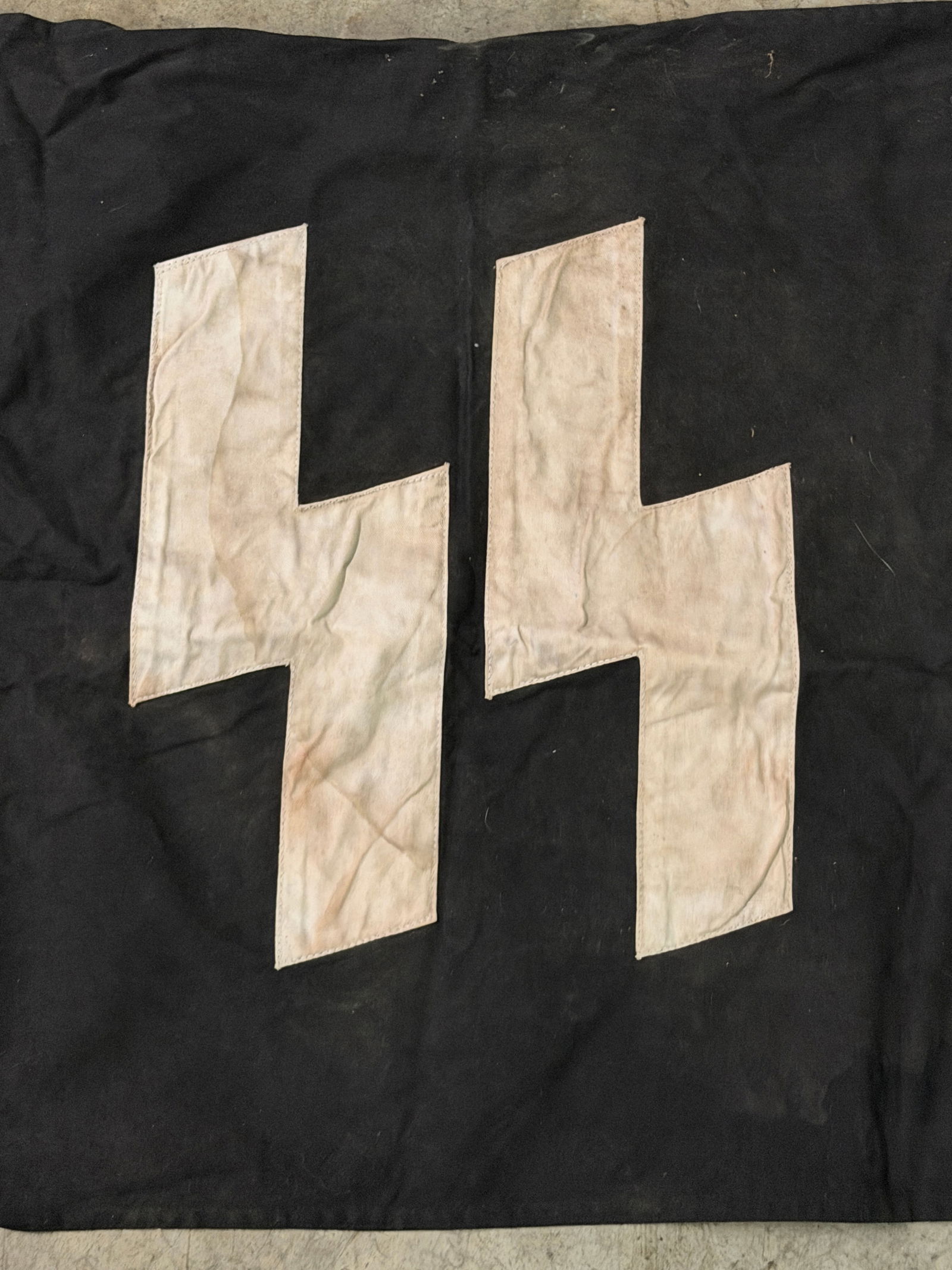 WWII German Waffen-SS Double Sig Rune Flag – Marked Example with Rope & Rings: World War II–era German Waffen-SS flag featuring the iconic double Sig (??) runes appliquéd in white cloth onto a black field. The runes are separately sewn, showing correct construction and materi