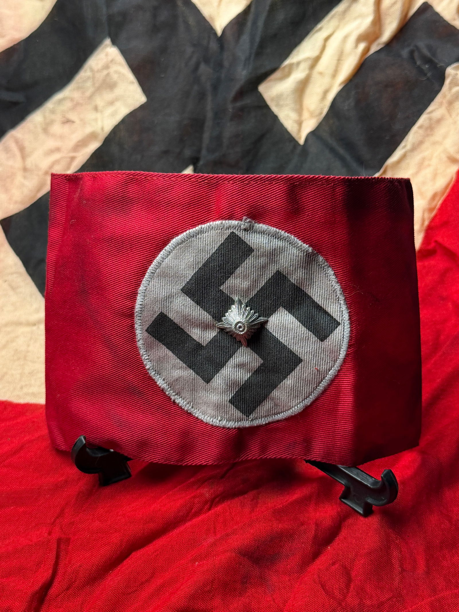NSDAP Party Armband with Political Leader’s Insignia, Nazi Germany, c. 1933–1945 & RZM Paper Tag: This red cloth armband bears the black swastika within a white roundel, the primary emblem of the National Socialist German Workers’ Party (NSDAP). Produced for wear on the left arm, such armbands s