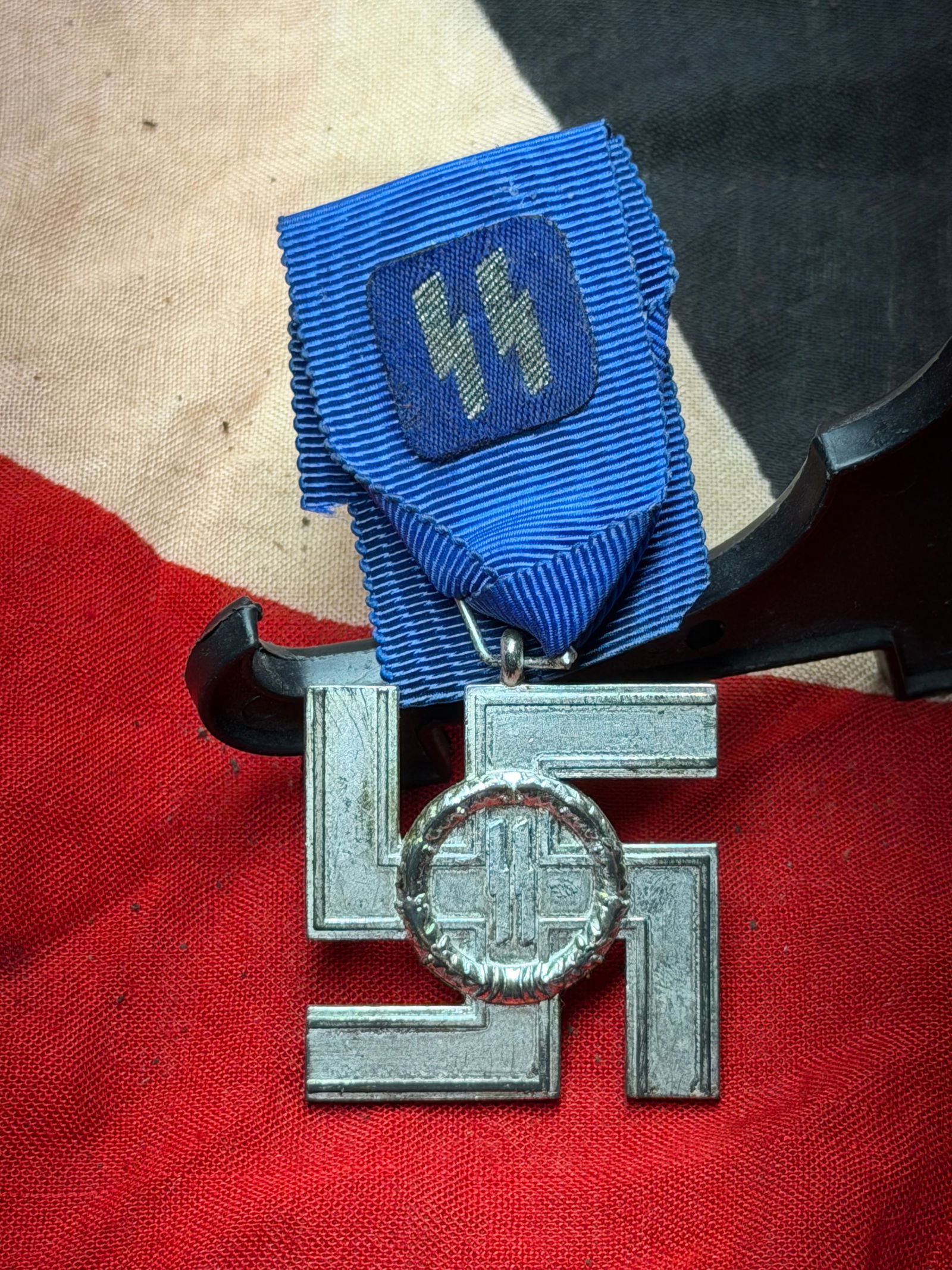 WW2 German SS Long Service Award with Ribbon and Suspension Bar: This medal is an original SS Long Service Award (SS-Dienstauszeichnung) from Nazi Germany, instituted to recognize length of service within the Schutzstaffel (SS). The decoration consists of a swastik