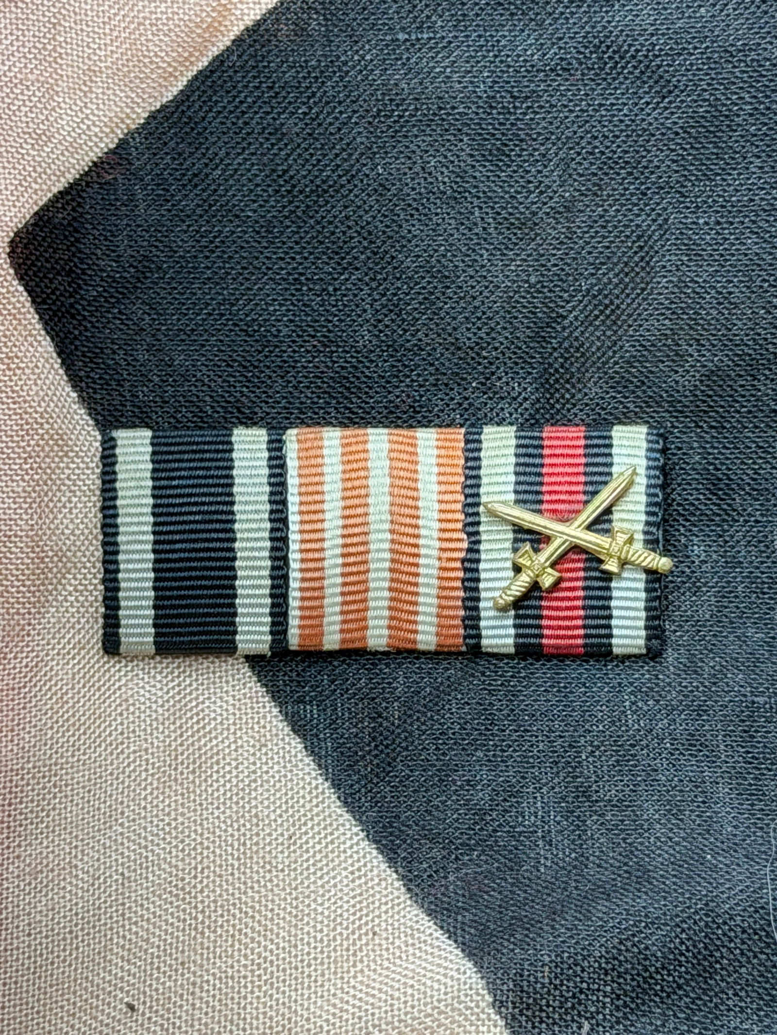 German WWII Ribbon Bar with Crossed Swords (War Merit Decoration): This ribbon bar dates to the Second World War and represents a German military award worn on the service uniform in place of the full medal. The ribbon’s distinctive color scheme—black, white, and
